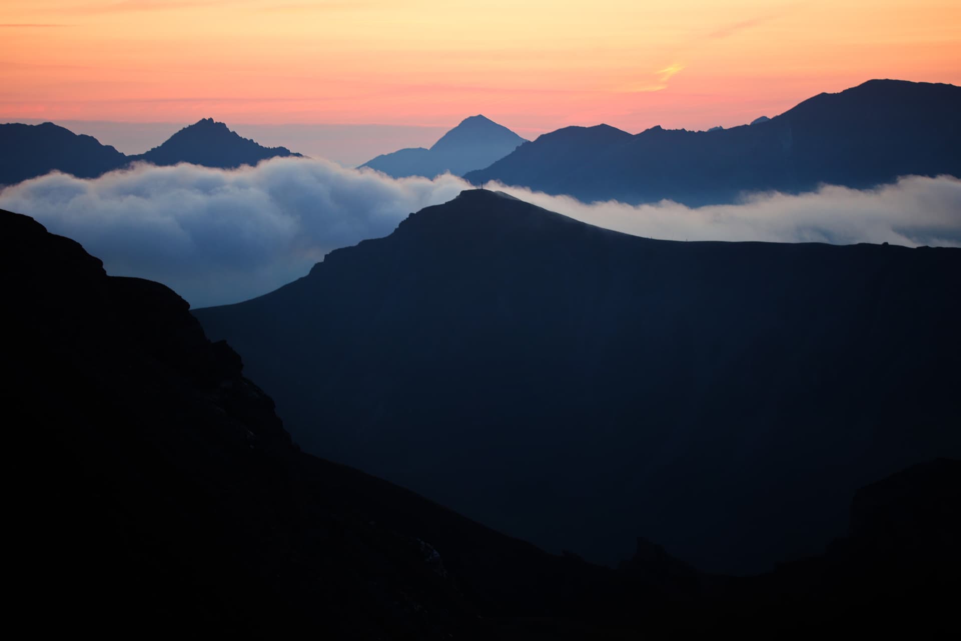 Gratschichten über einem Nebelmeer im rosa Morgenlicht