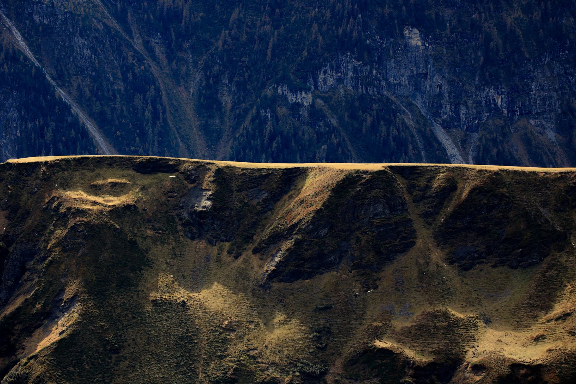 Plateaukante im goldenen Licht über dunklem, bewaldetem Tal