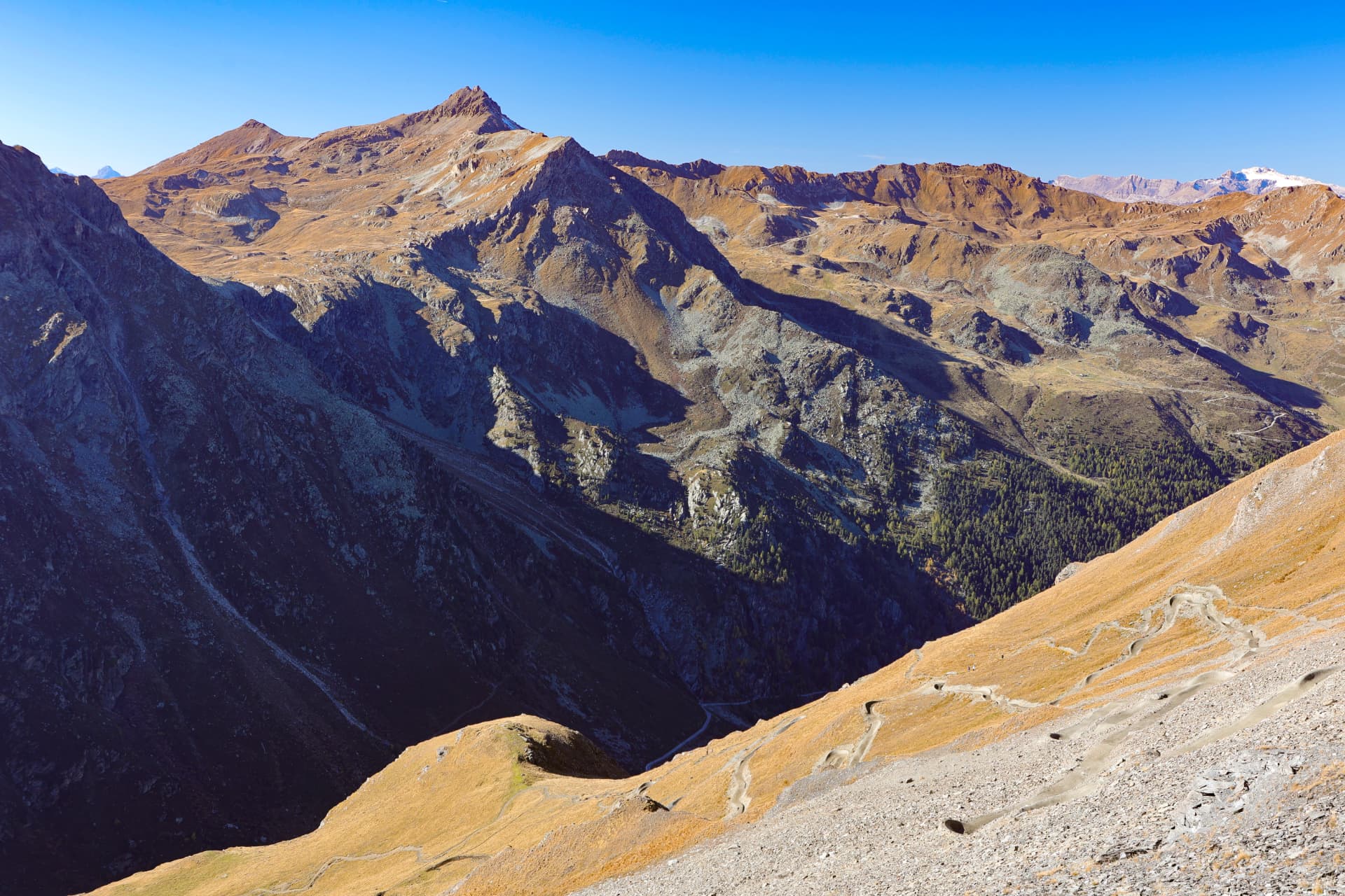 Gewundener Bergweg an einem goldenen Hang über dem Tal