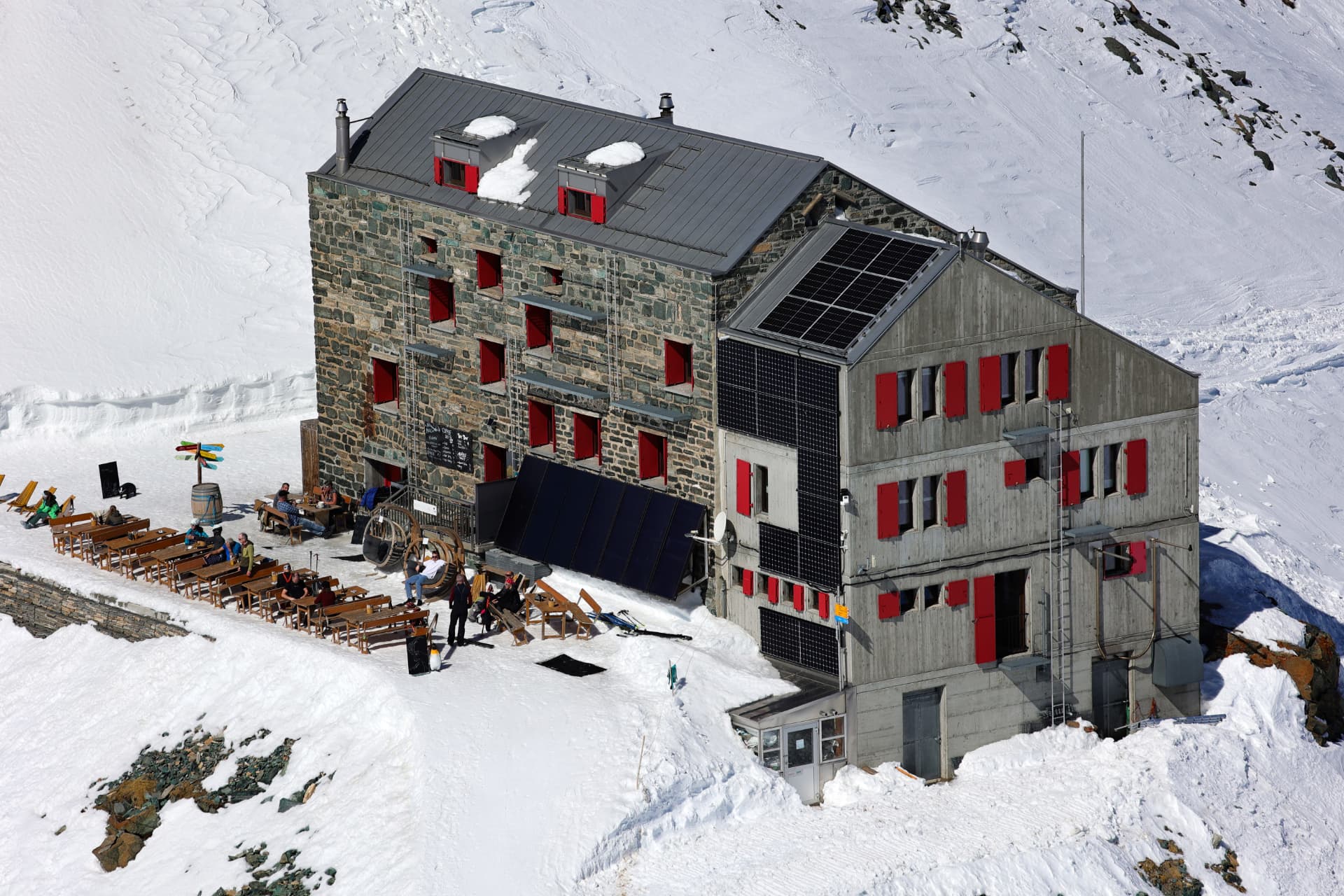 Britanniahütte SAC von nahe — sonnige Terrasse voller Skifahrer