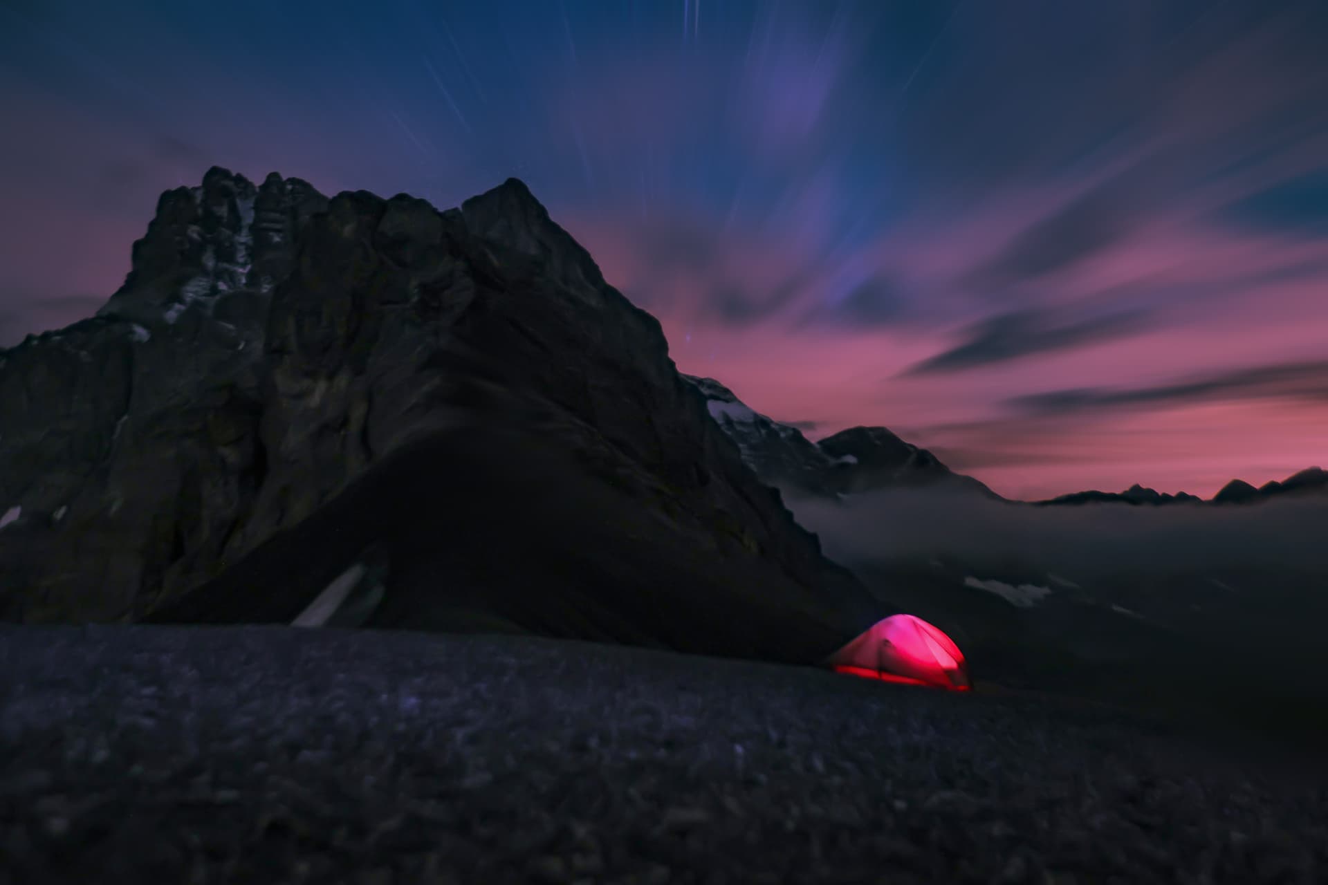 Rotes Zelt auf dem Pass unter rosafarbenem Nachthimmel