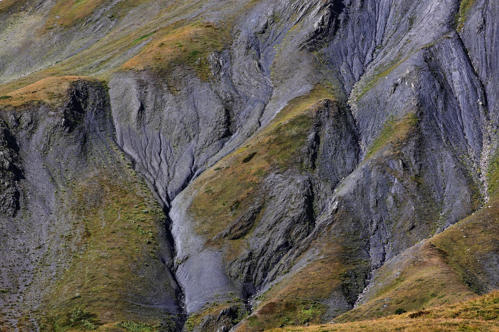 Erosionsrinnen an einem felsigen Hang mit Grasflächen