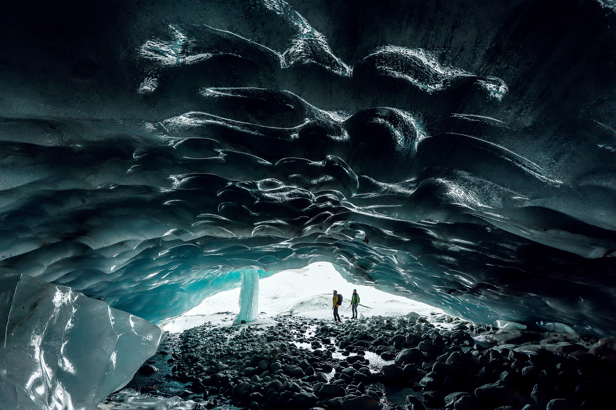 Zwei Personen unter dem grossen Eisgewölbe des Zinalgletschers