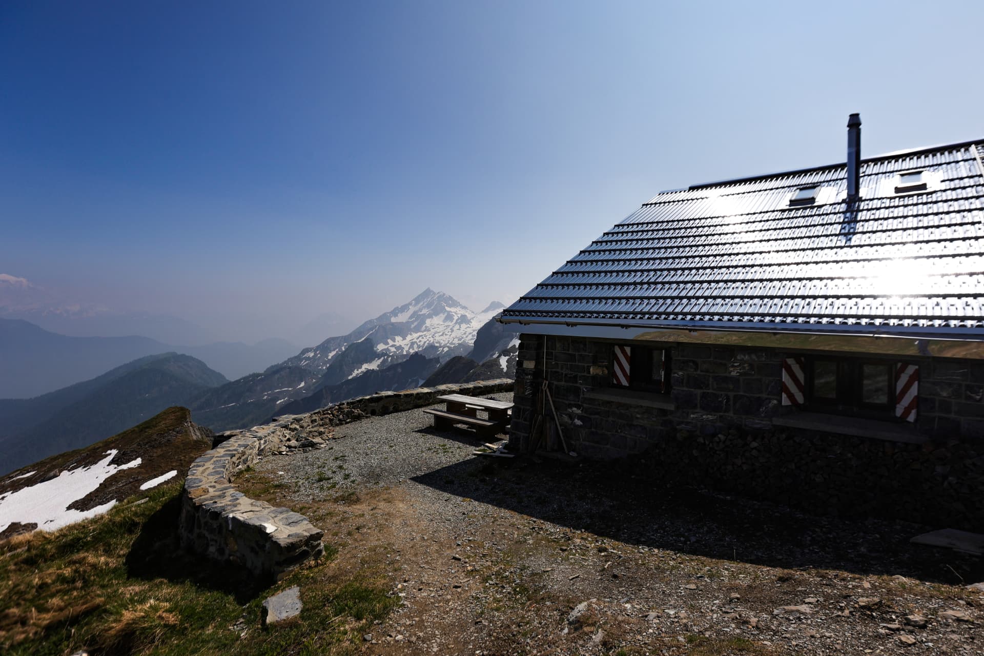 Cabane Rambert CAS — Steinhütte mit Metalldach vor schneebedeckten Gipfeln