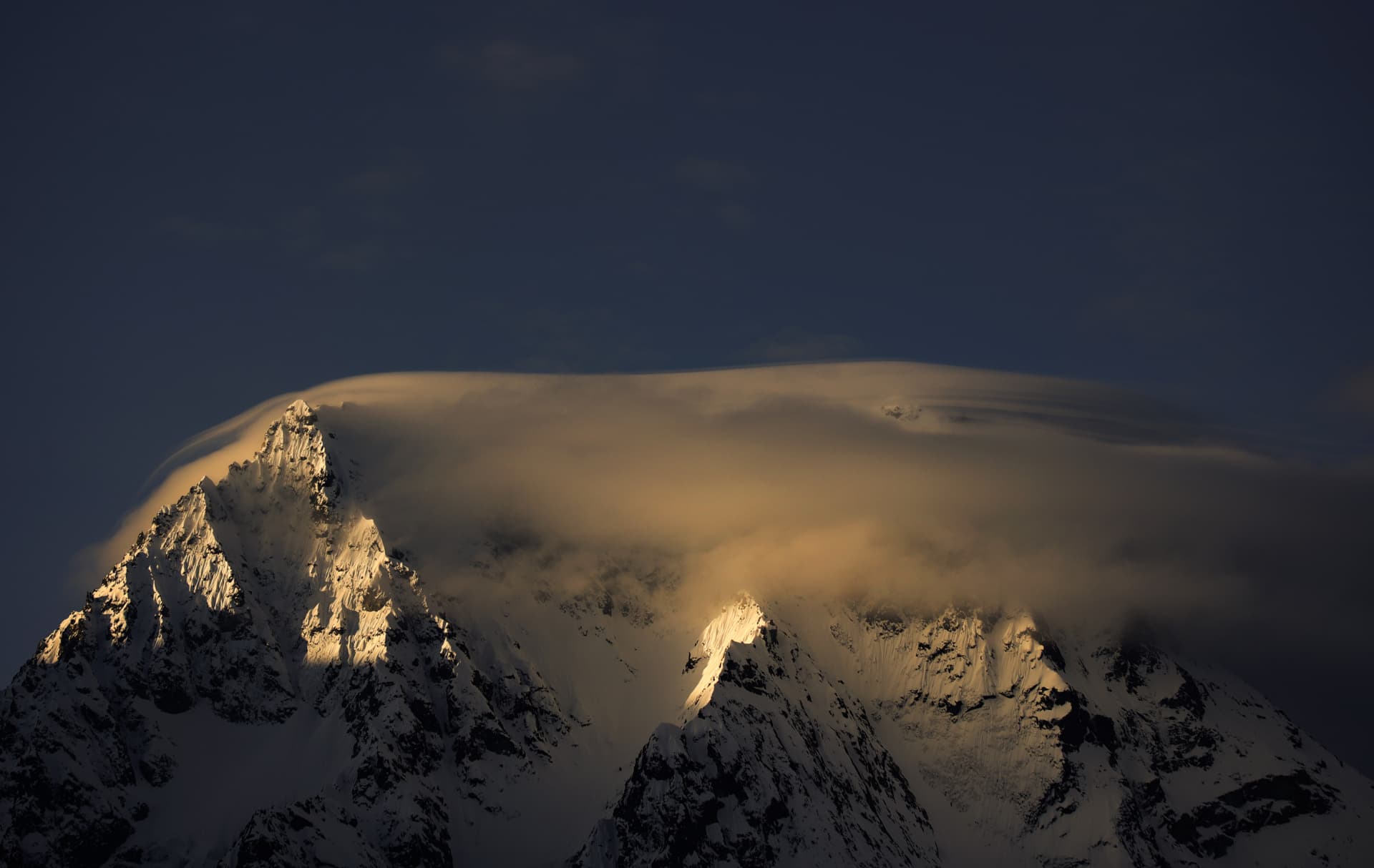 Linsenwolke im goldenen Licht über einem verschneiten Gipfel der französischen Alpen