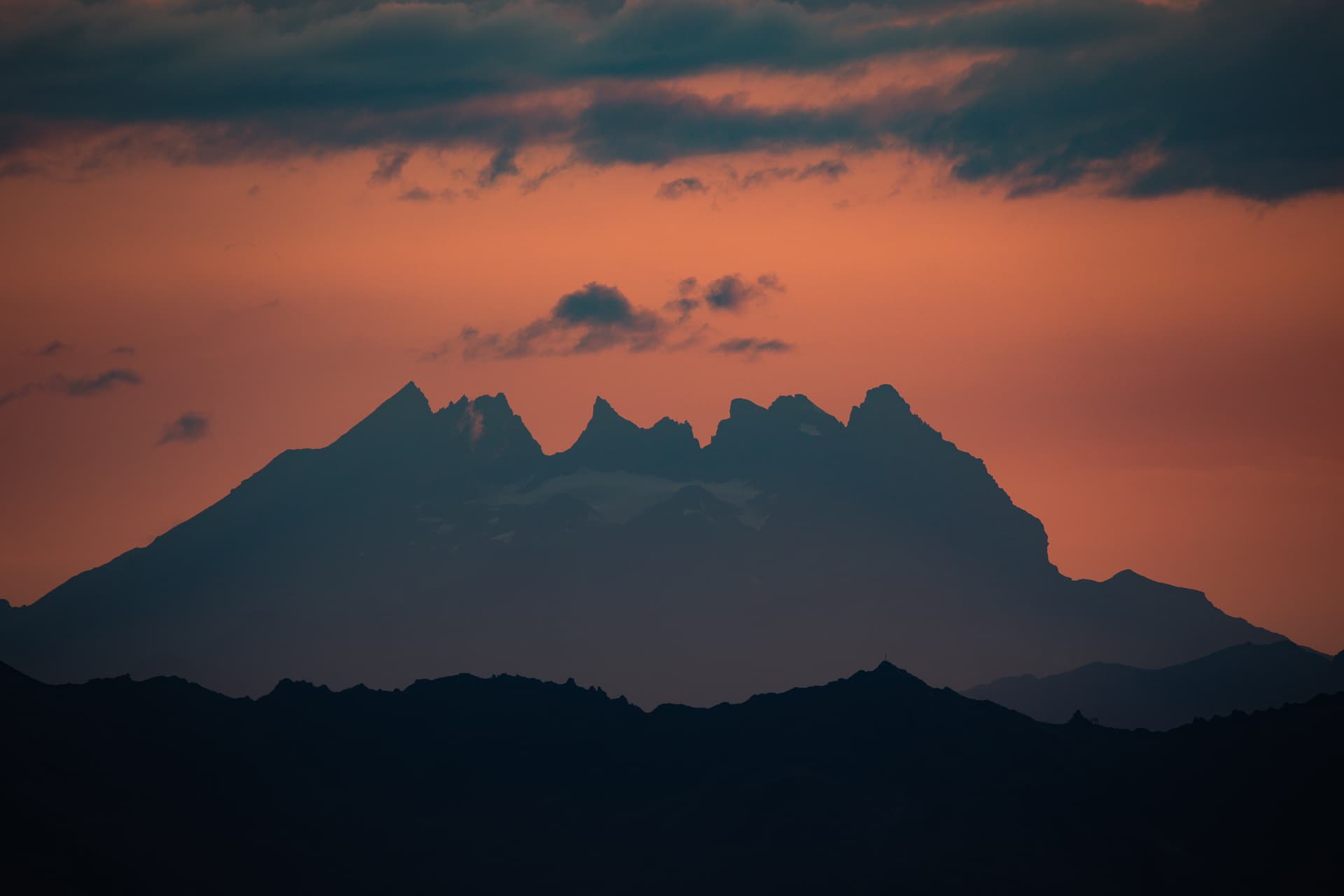 Gratsilhouetten vor orangem Himmel nach Sonnenuntergang