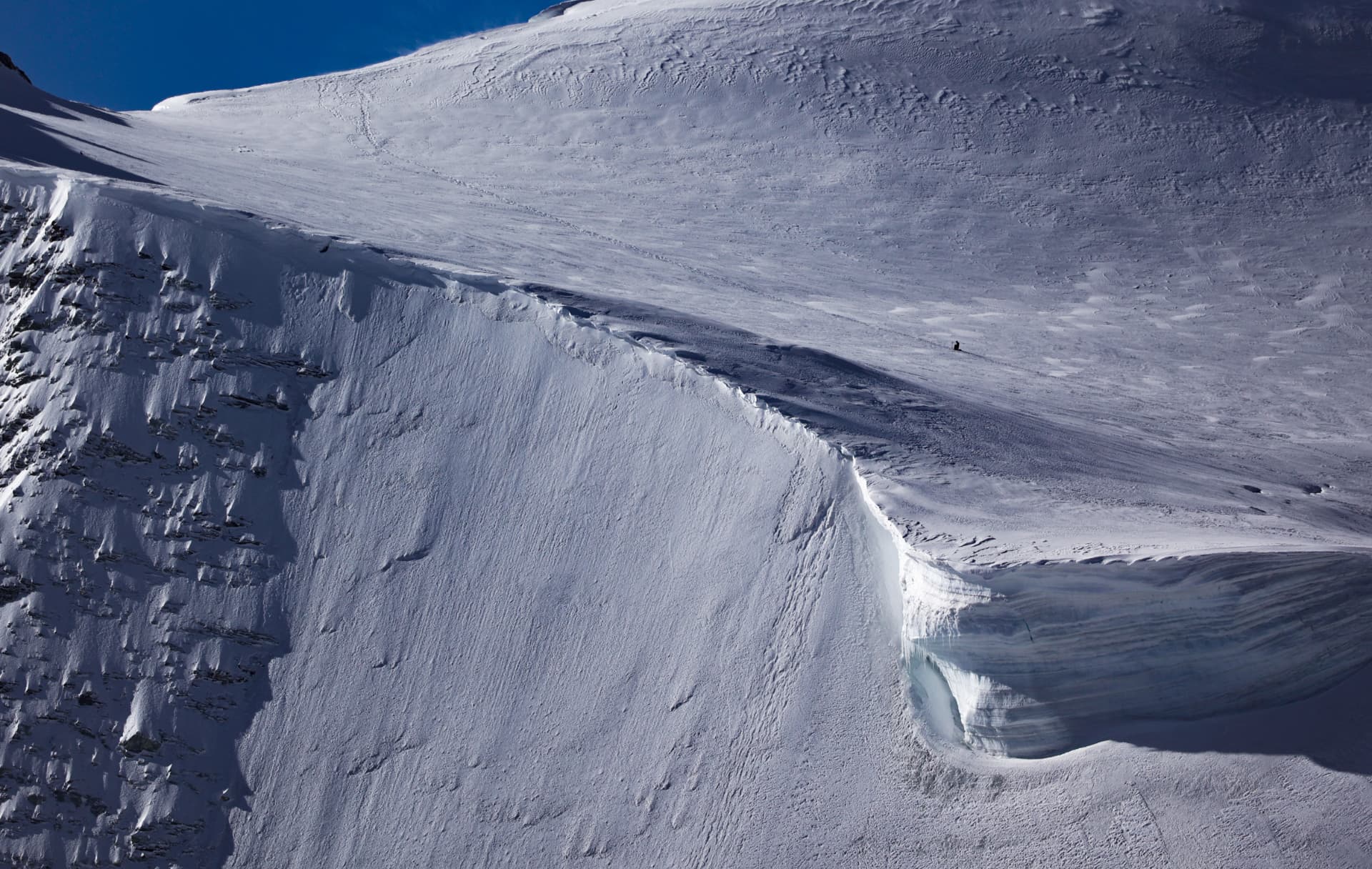Enorme Schneewand über dem Gletscher, ein Wanderer wie ein Punkt