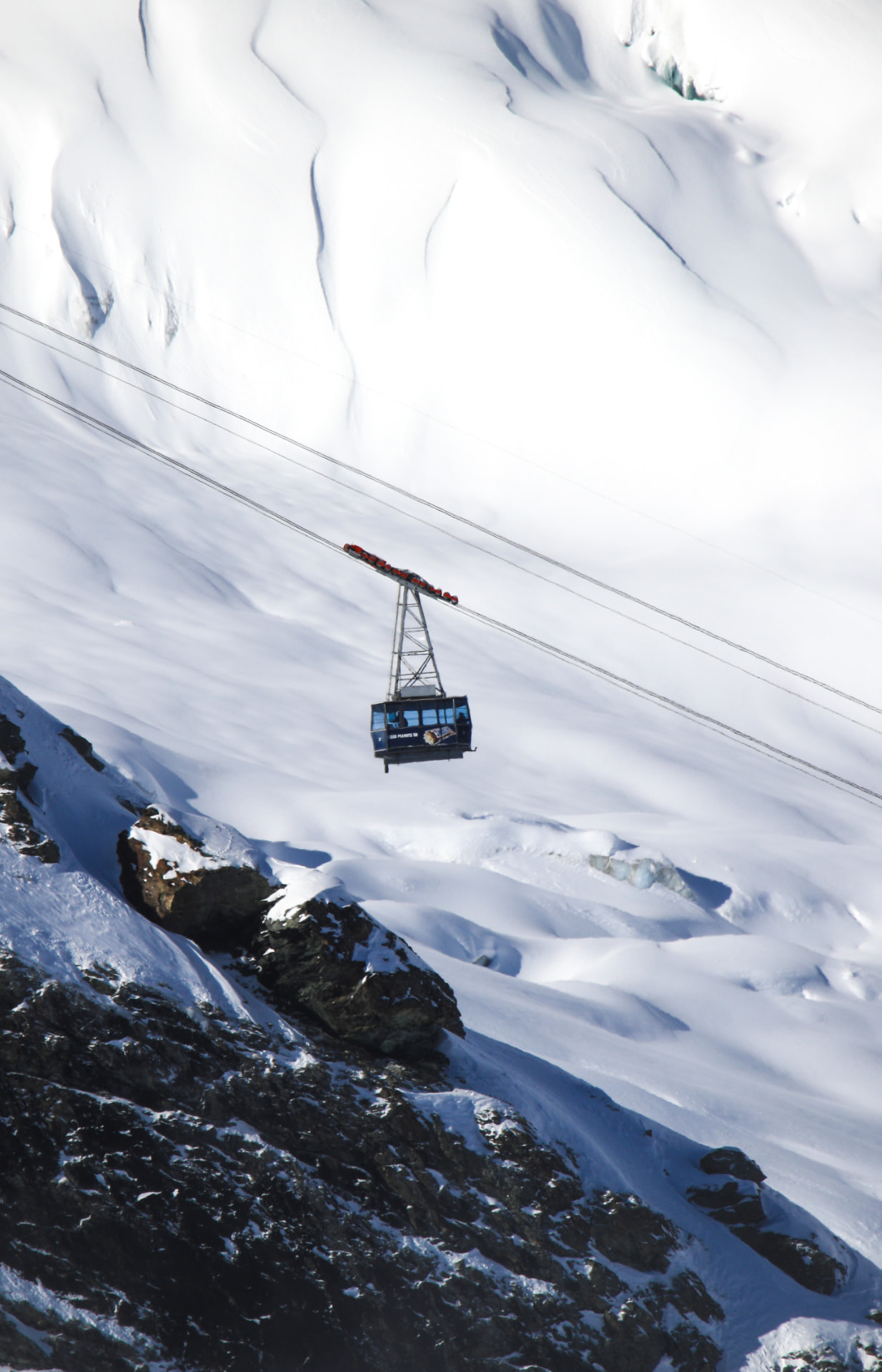 Kabine der Bahn über einem verschneiten Hang hoch über Saas-Fee