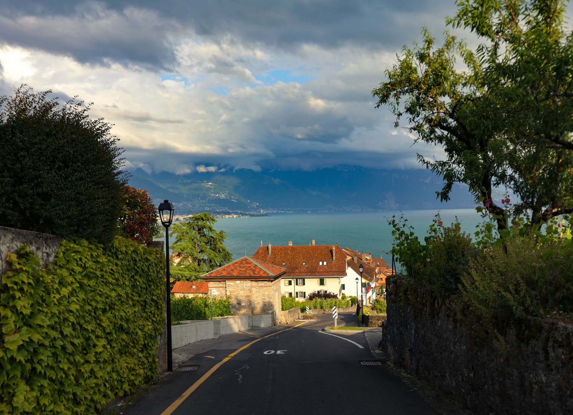 Schmale Rebstrasse in Lavaux mit Blick auf den See und Wolken über den Alpen