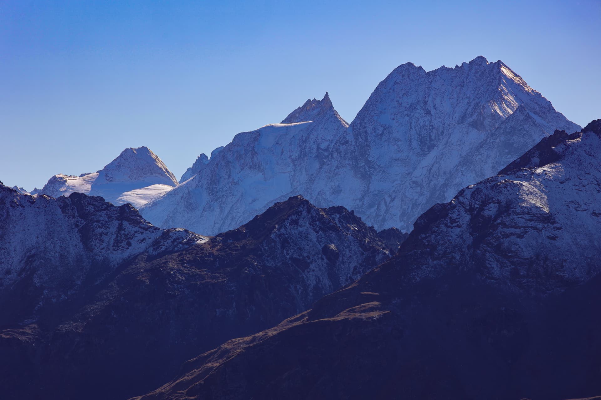 Verschneite Gipfel und Felswände unter wolkenlosem Himmel