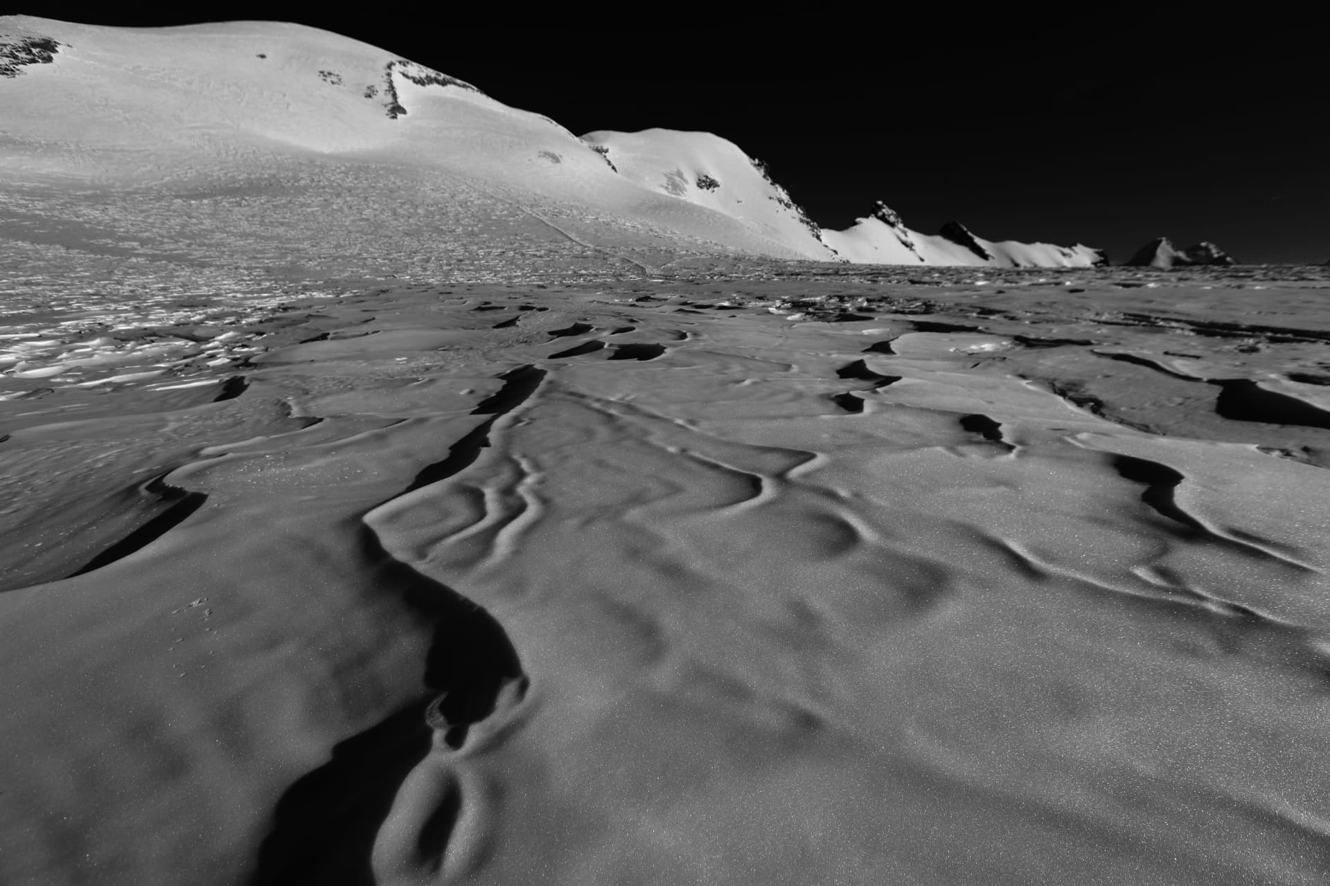 Schwarzweisse Struktur von verblasenem Schnee und Sastrugi auf dem Gletscher