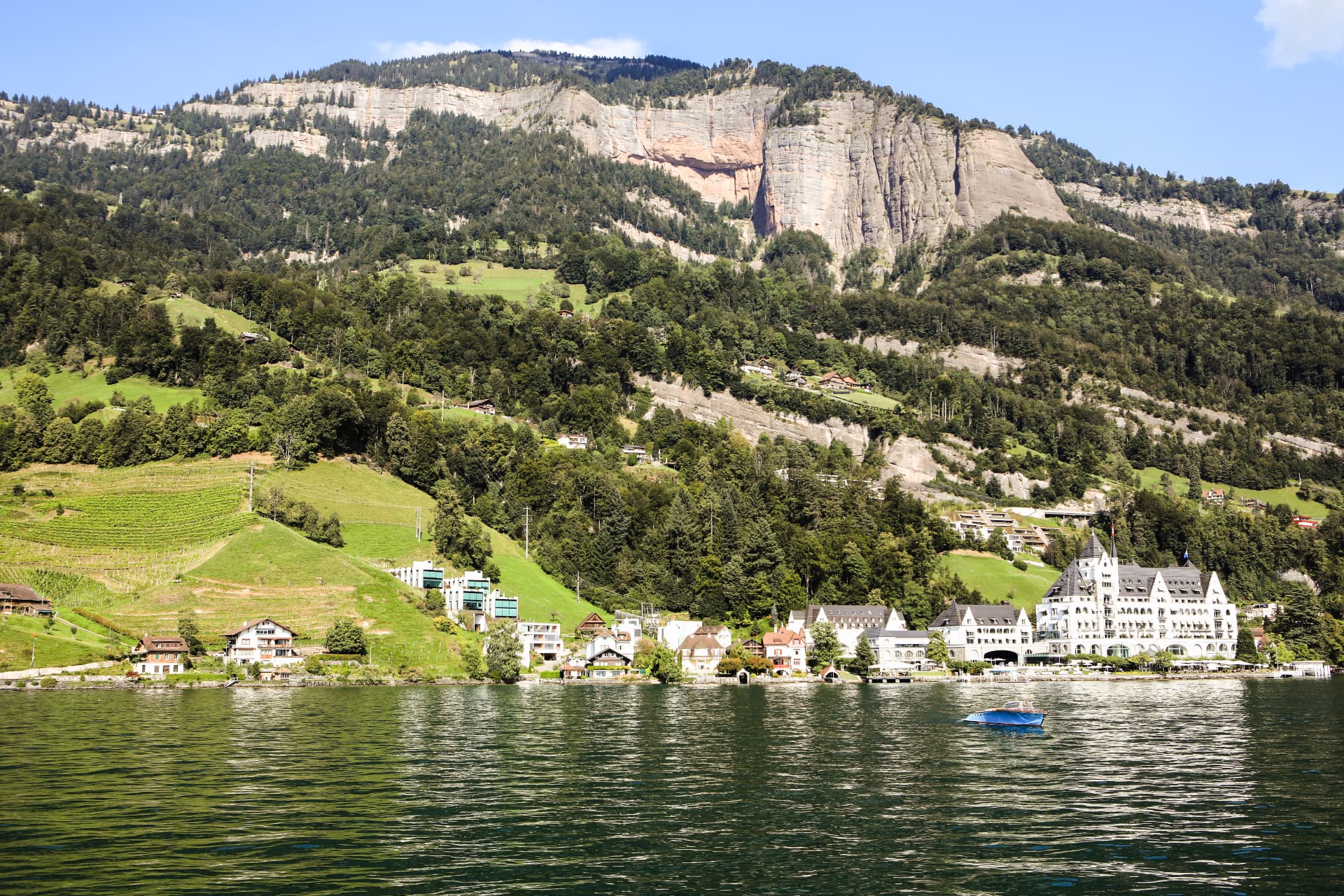 Ufer des Vierwaldstättersees mit Hotels und Rebbergen unter einer Felswand