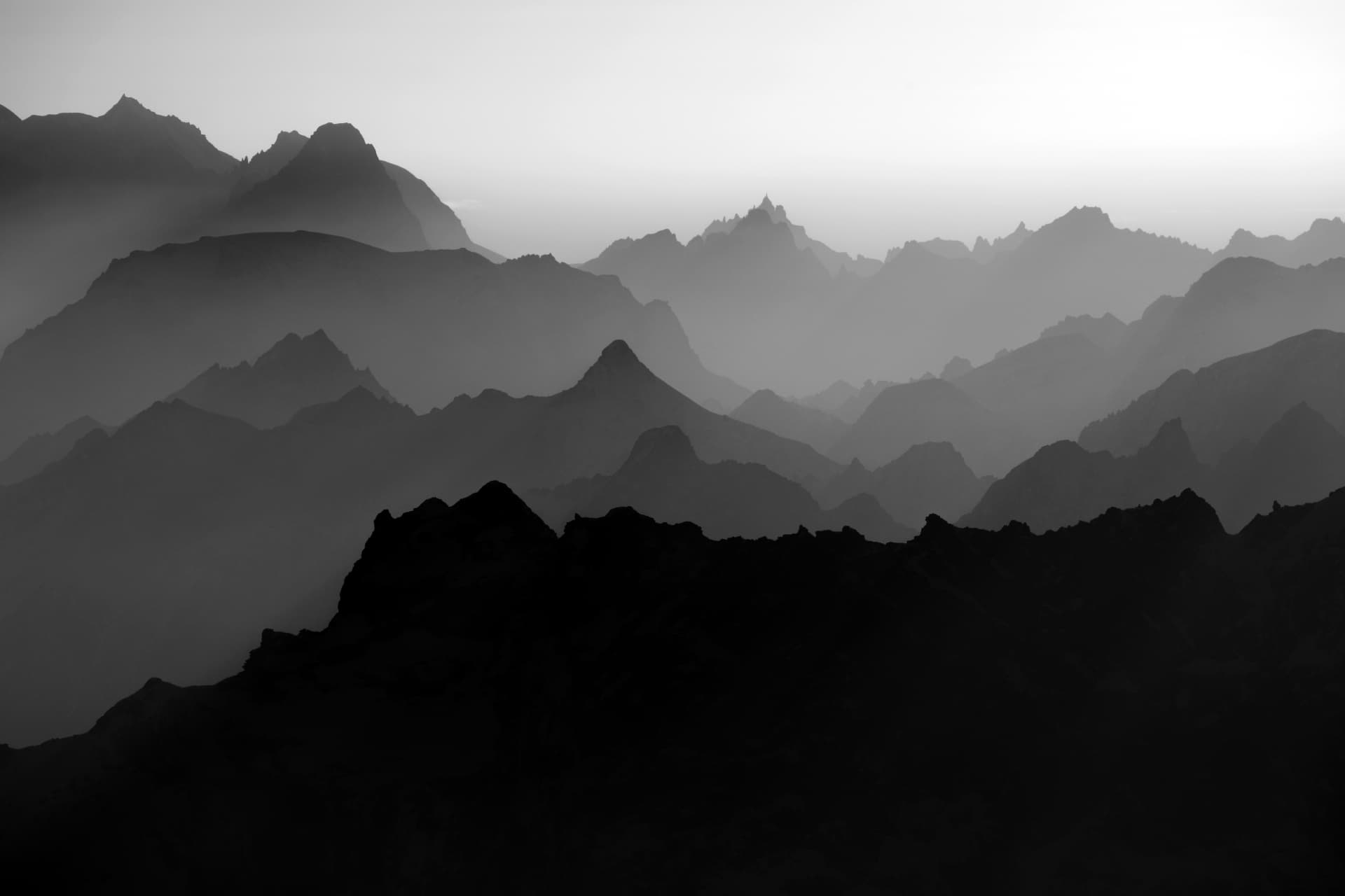 Gestaffelte alpine Bergkämme im Dunst, schwarzweiss