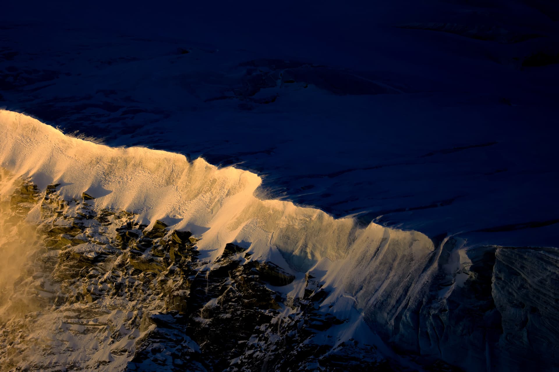 Beleuchteter Schneegrat vor tiefem Bergschatten
