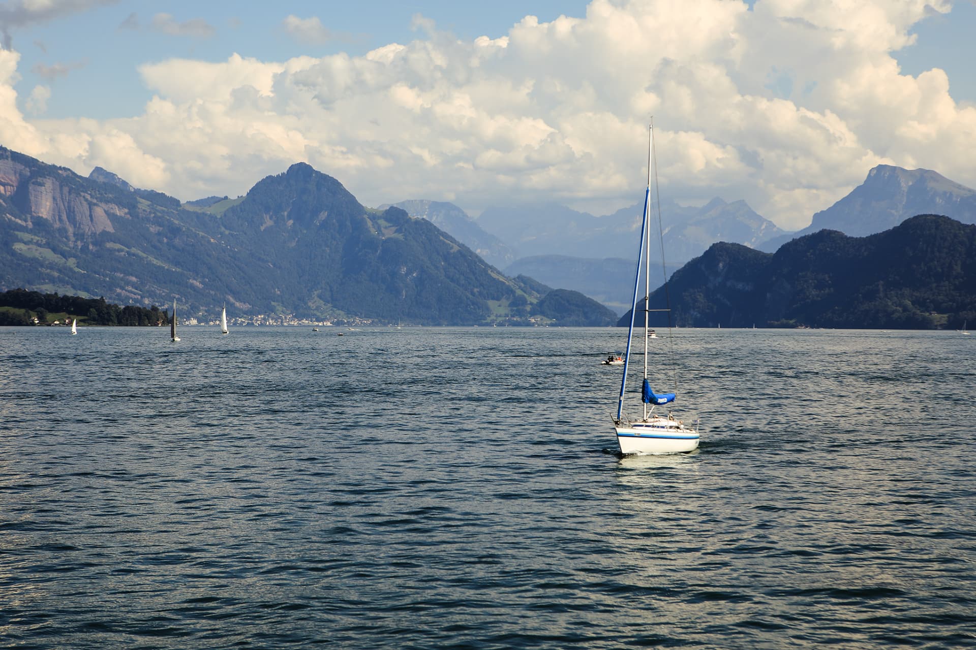 Segelboot auf dem Vierwaldstättersee mit gestaffelten Bergen und Quellwolken