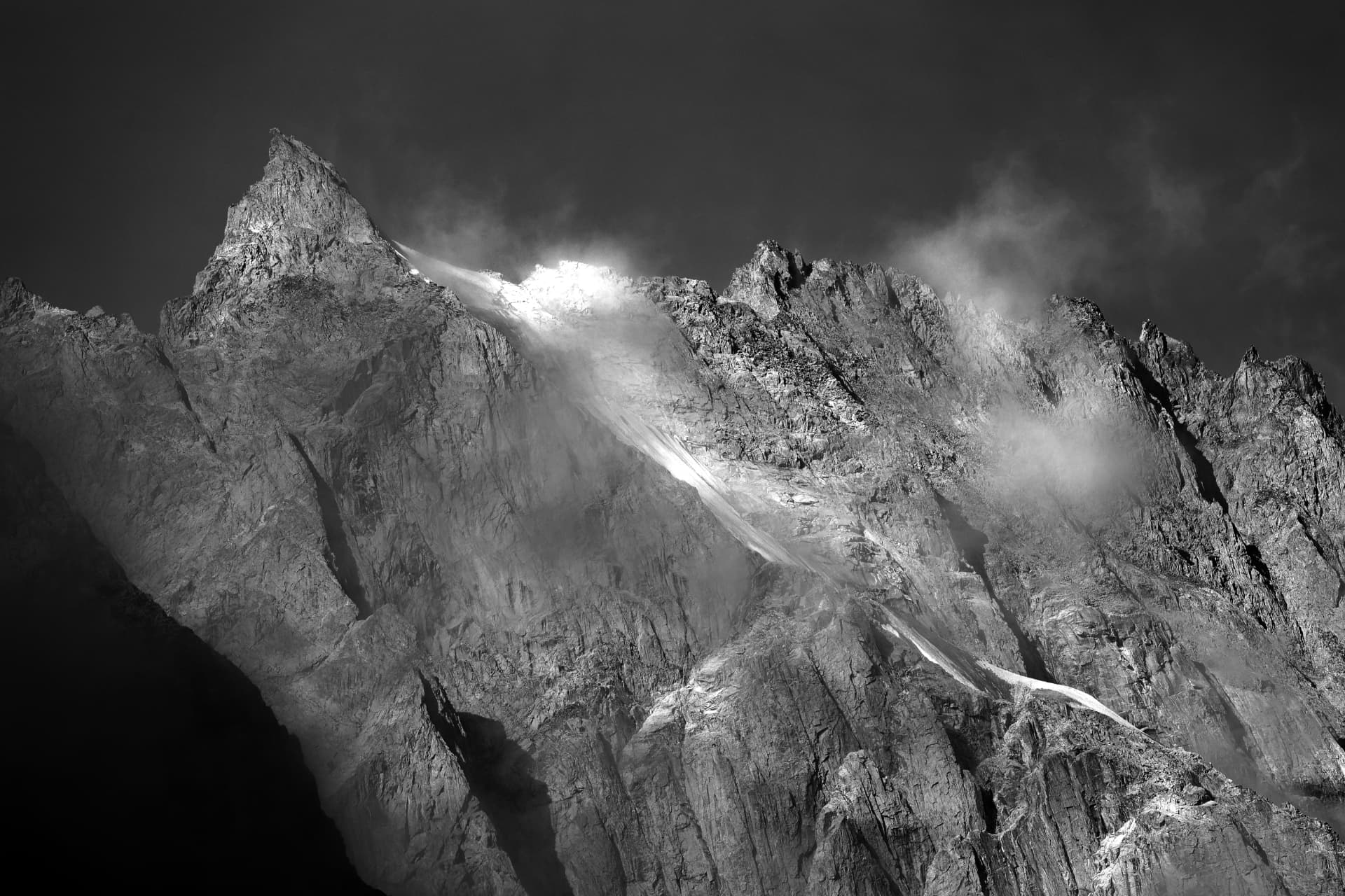 Besonnte Gletscherzunge vor dunklem Grat, in Schwarzweiss