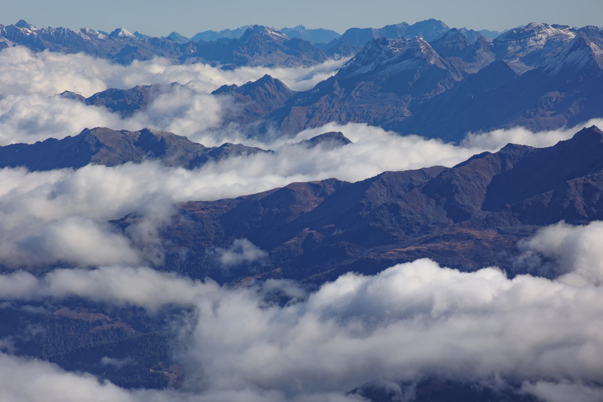 Weites Panorama gestaffelter Alpenkämme und Wolken