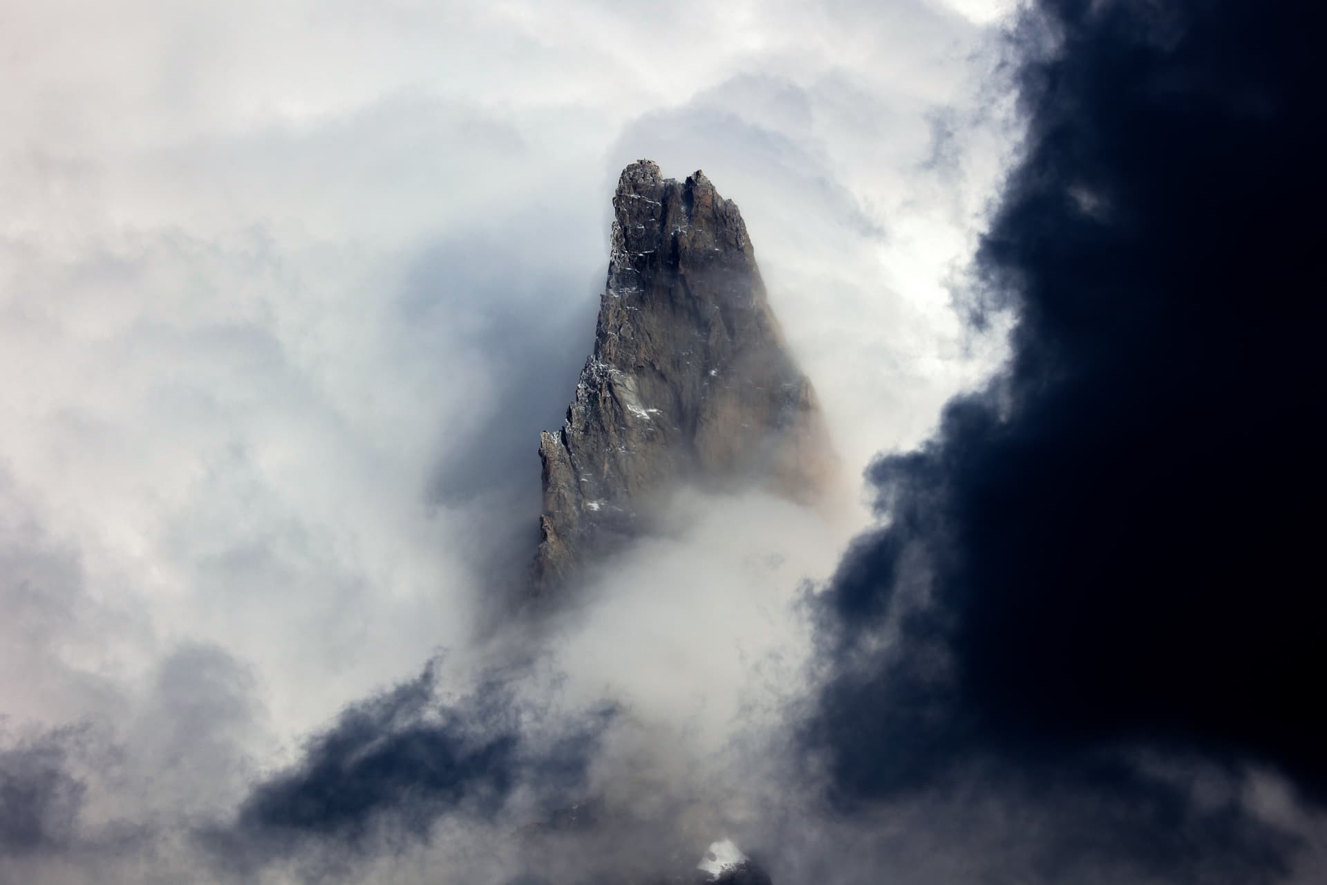 Felsnadel, die aus wirbelnden Wolken auftaucht
