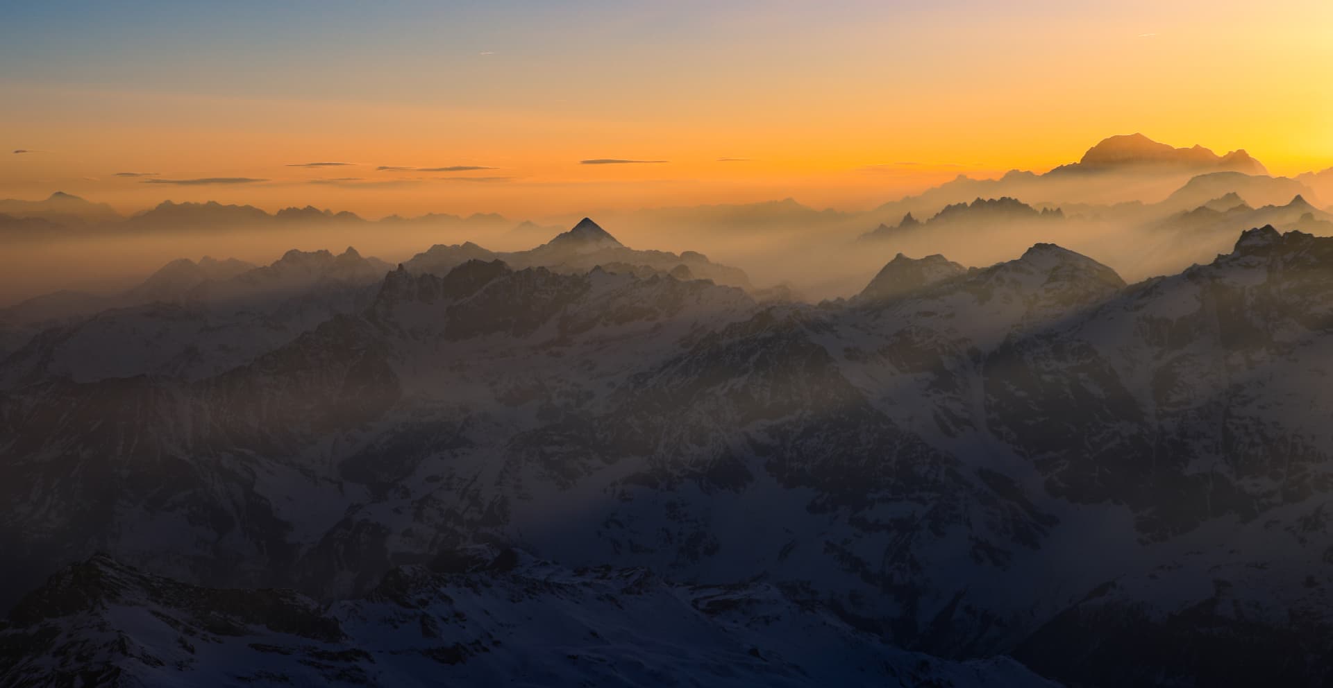 Weites Panorama alpiner Grate im goldenen Morgendunst mit Mont Blanc am Horizont