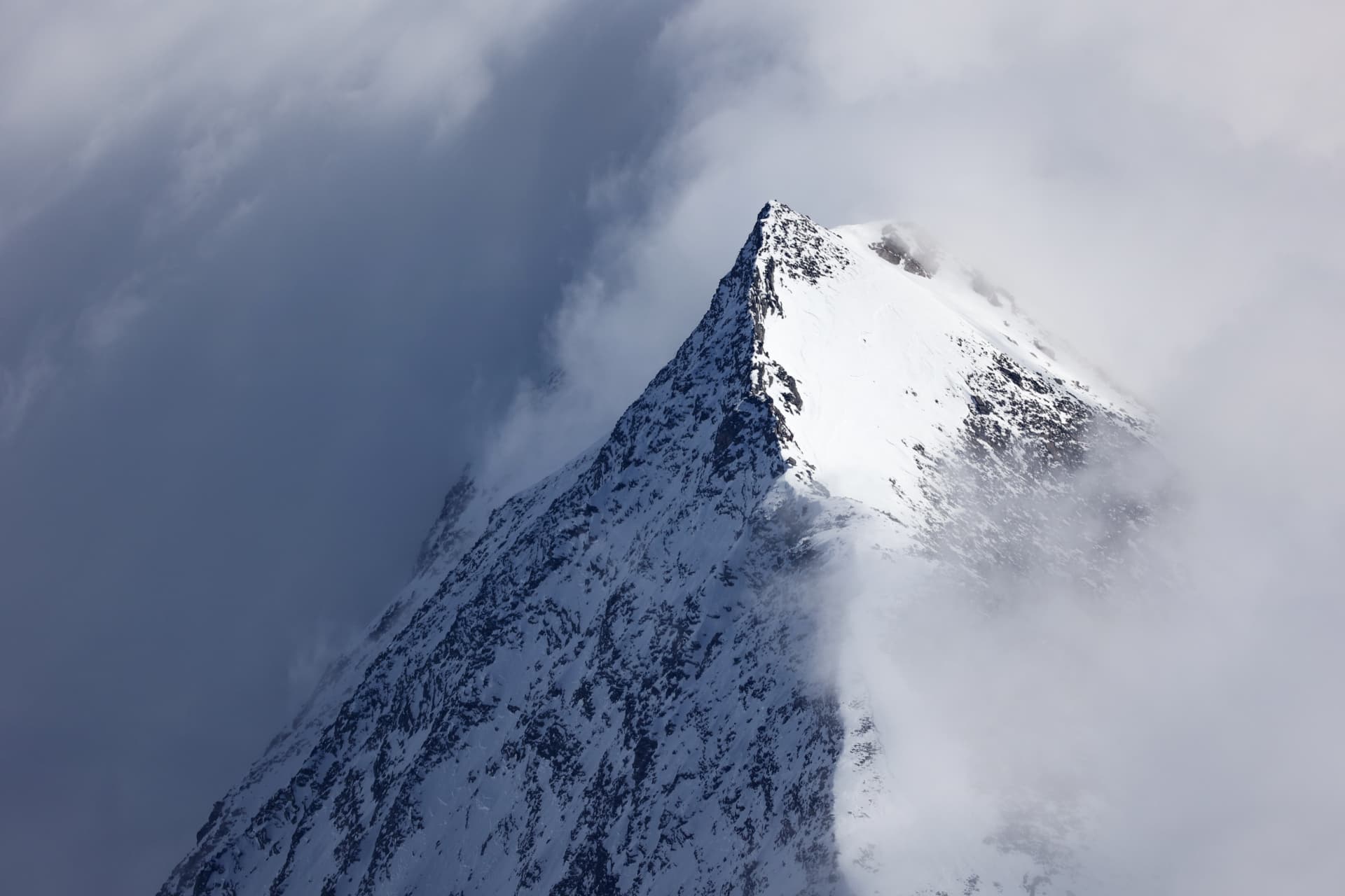 Steiler Schneegrat teilweise von Wolken umhüllt