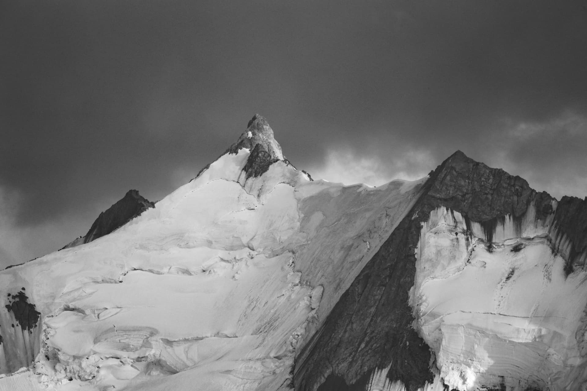 Schwarzweiss-Aufnahme eines scharfen Gipfels über Gletscher und Schneefeld