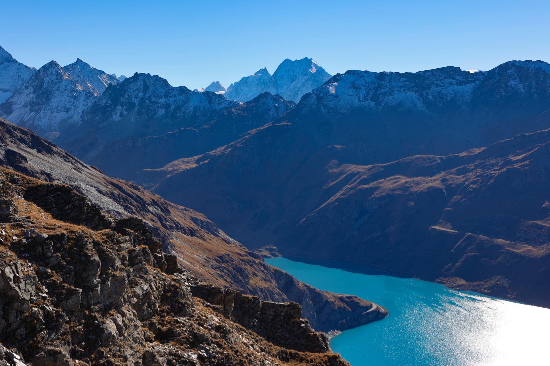 Türkisfarbener See unter gestaffelten Alpenkämmen