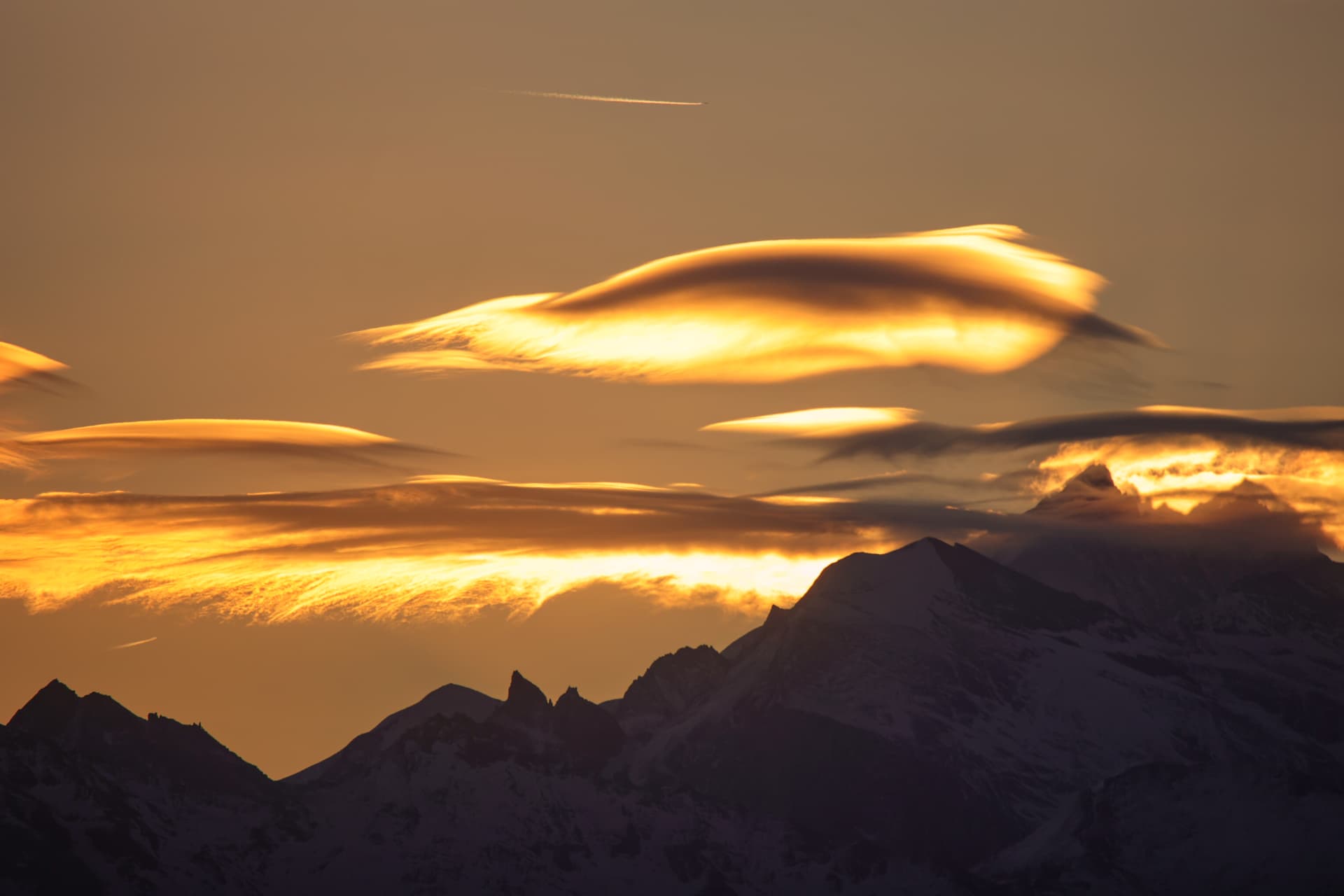 Golden angeleuchtete Lenticularis-Schichten über den Graten
