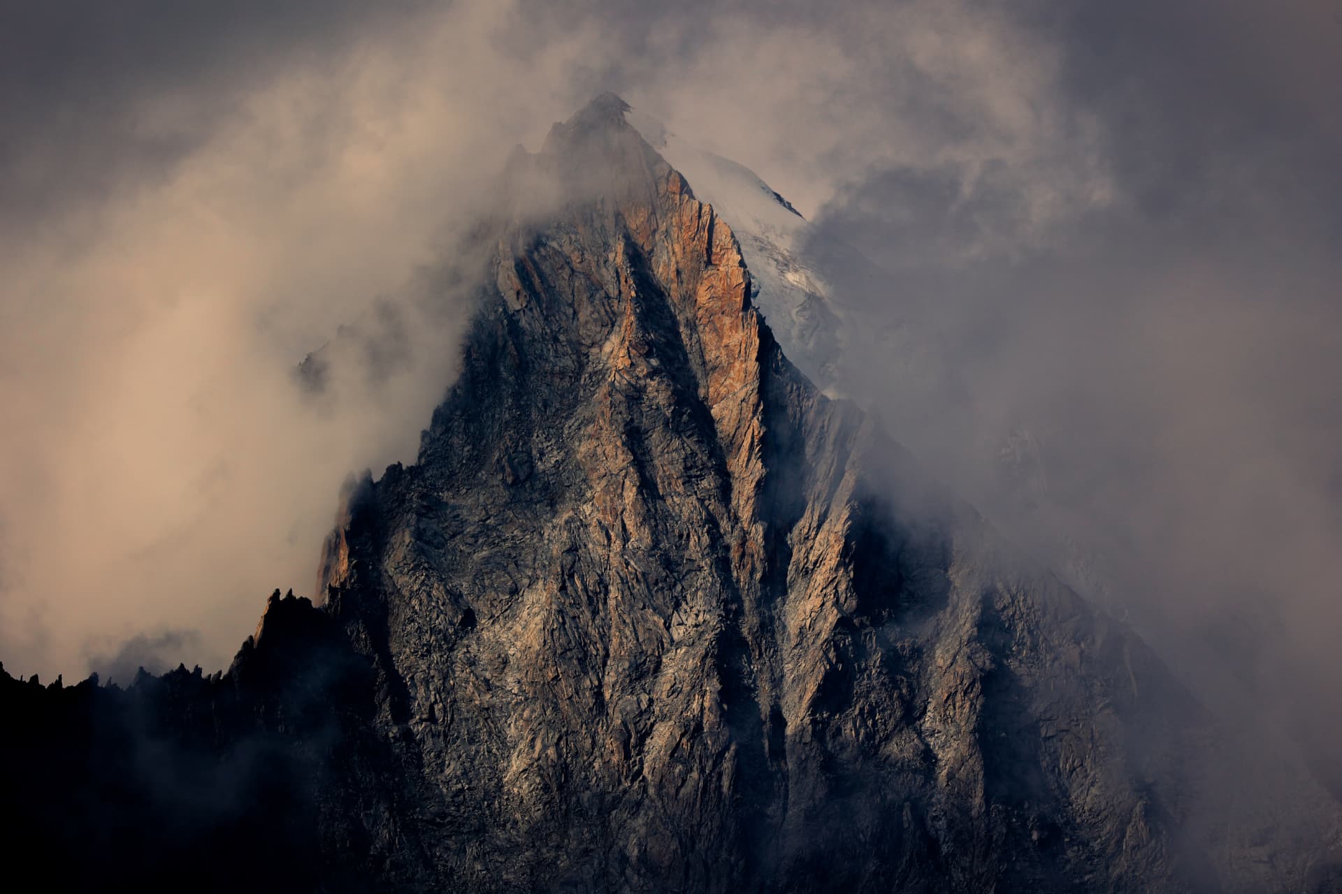 Beleuchtete Felswand des Bettmerhorns zwischen Wolken