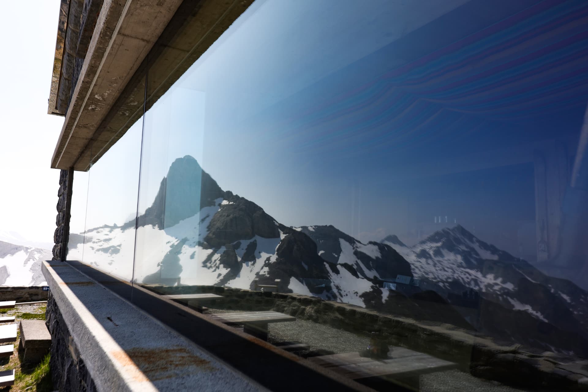 Schneebedeckte Berge spiegeln sich in der Glasfassade der Hütte