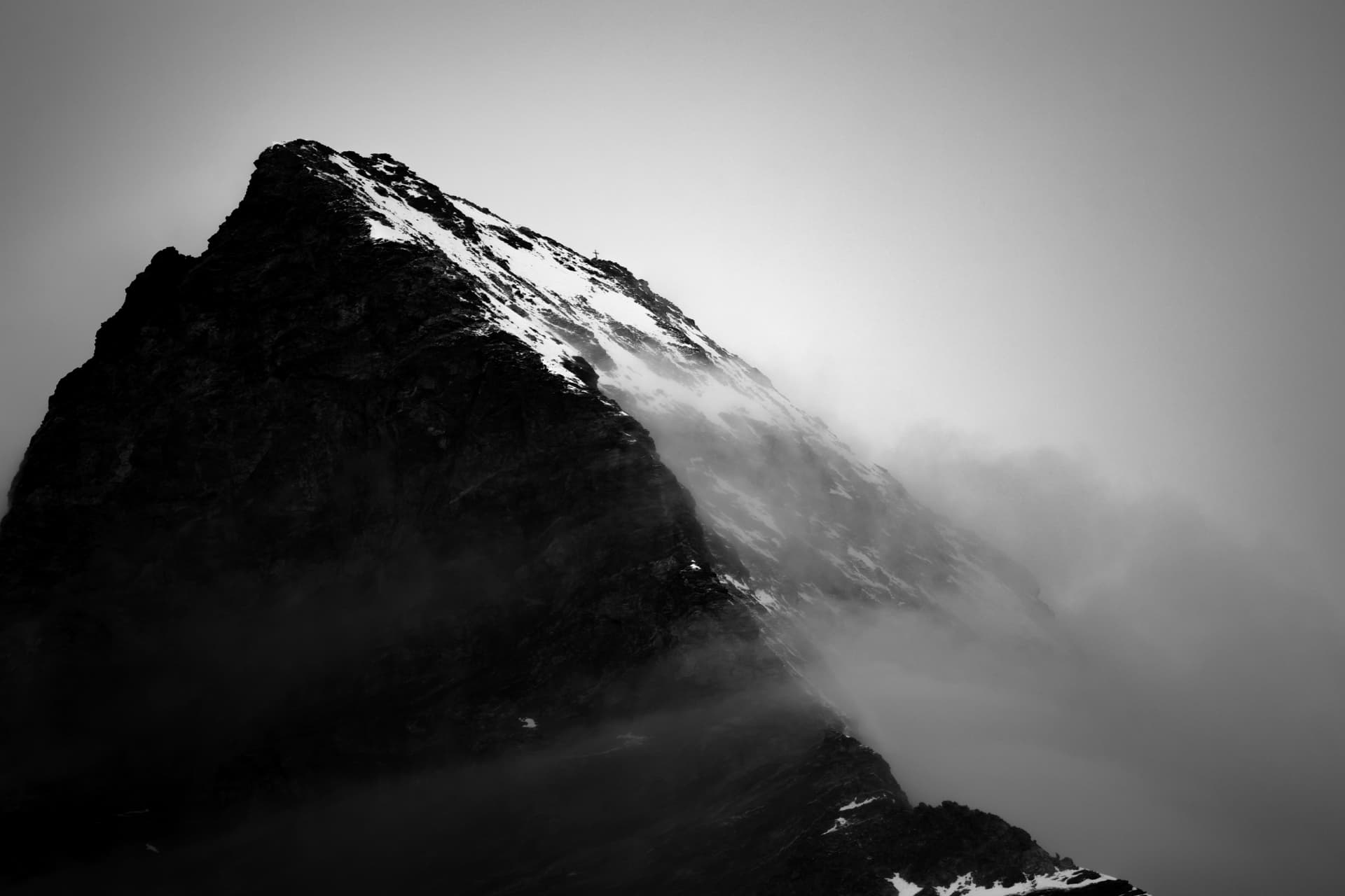 Gipfelkreuz am Grat im Nebel, schwarzweiss