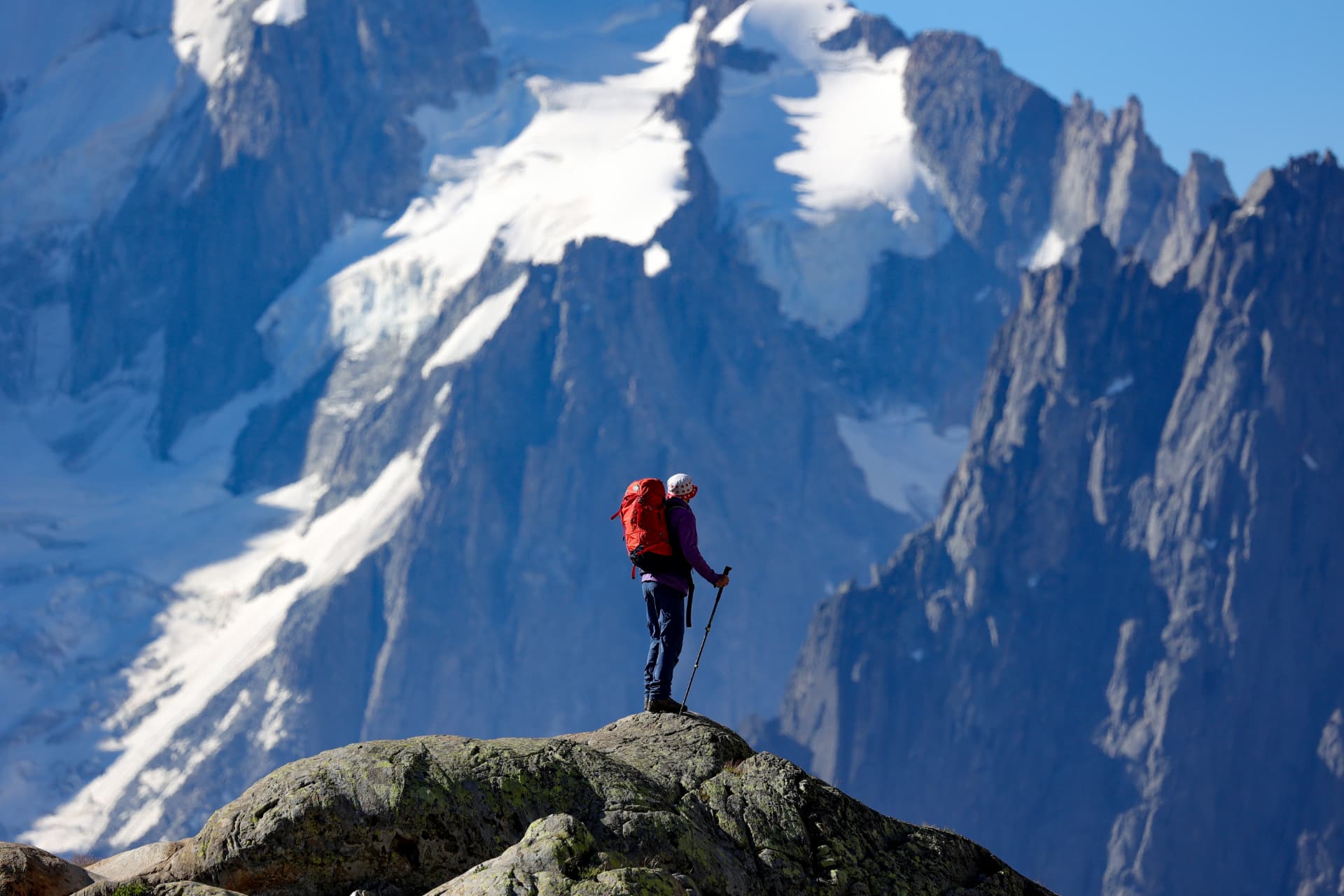 Silhouette eines Wanderers mit rotem Rucksack vor dem Gletscher