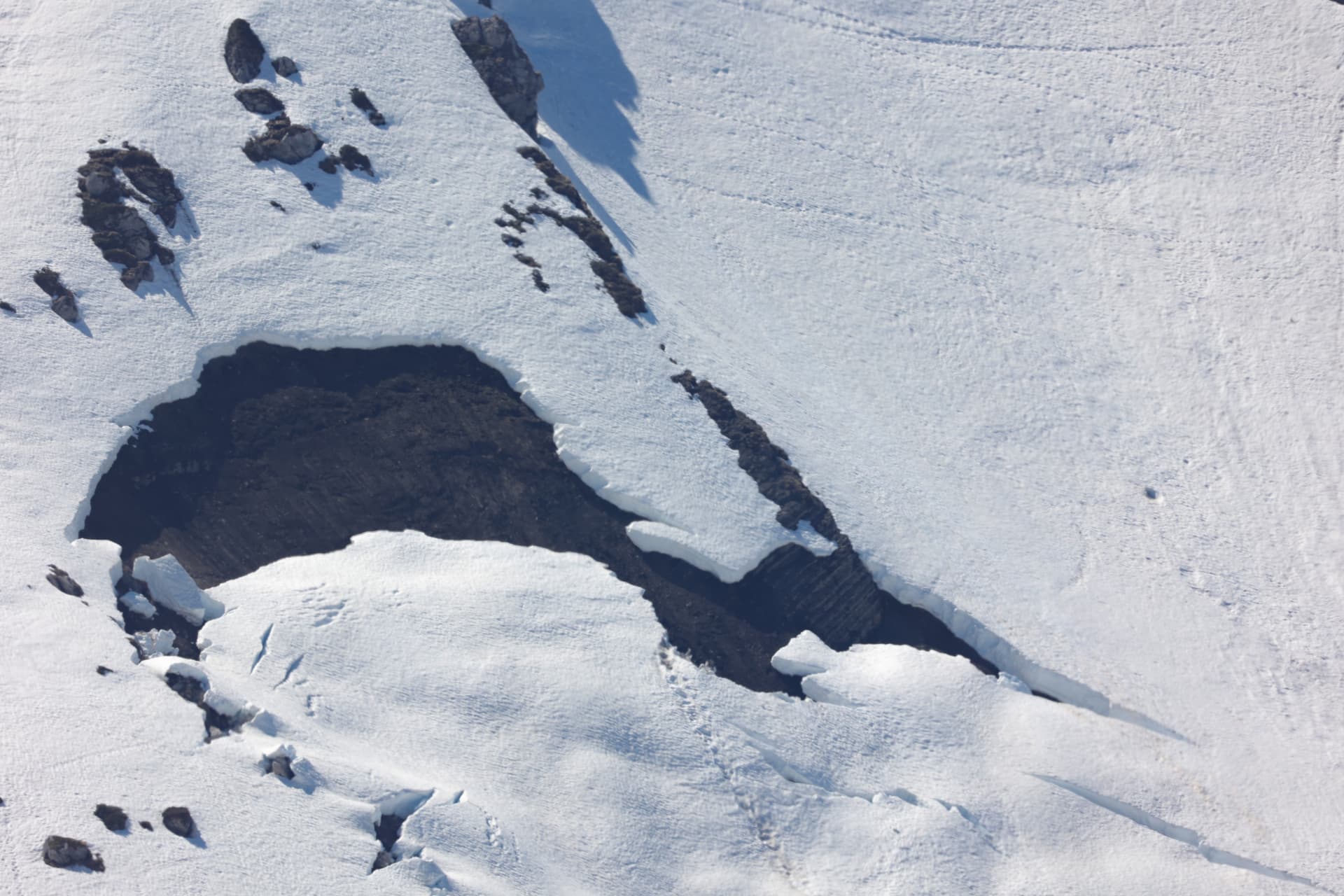 Freigelegter Boden und Felsen im Frühlingsschnee
