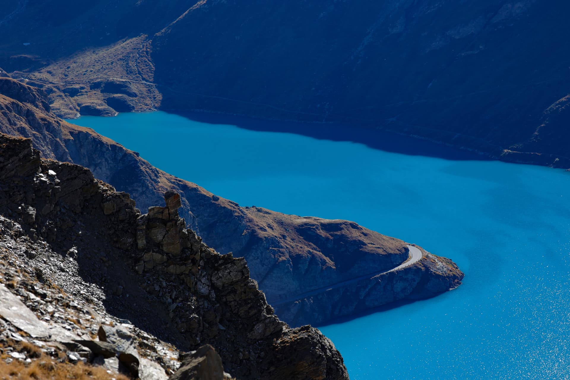 Türkisfarbener Alpensee mit Uferstraße von oben