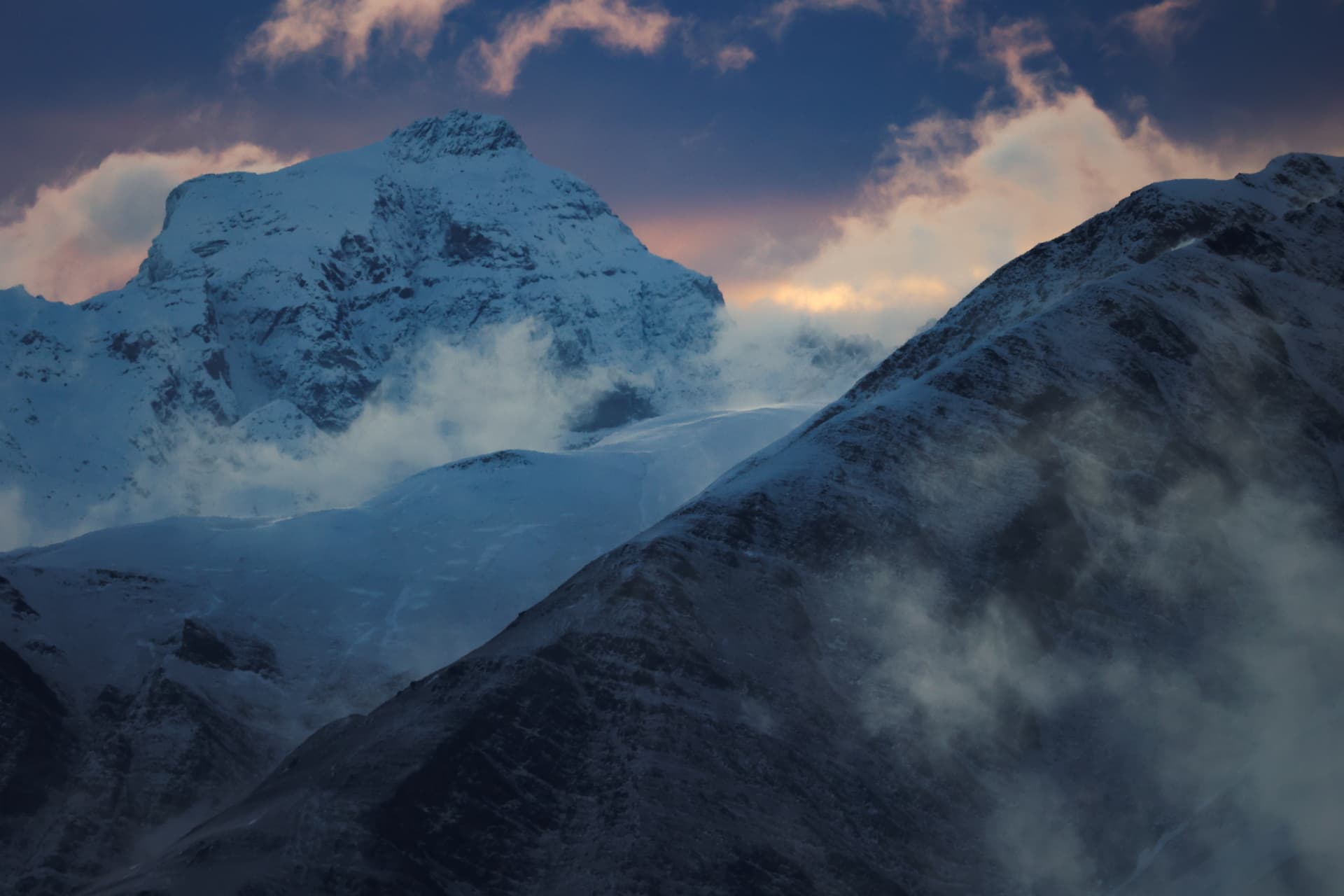 Verschneites Massiv taucht aus Wolken und Nebel auf