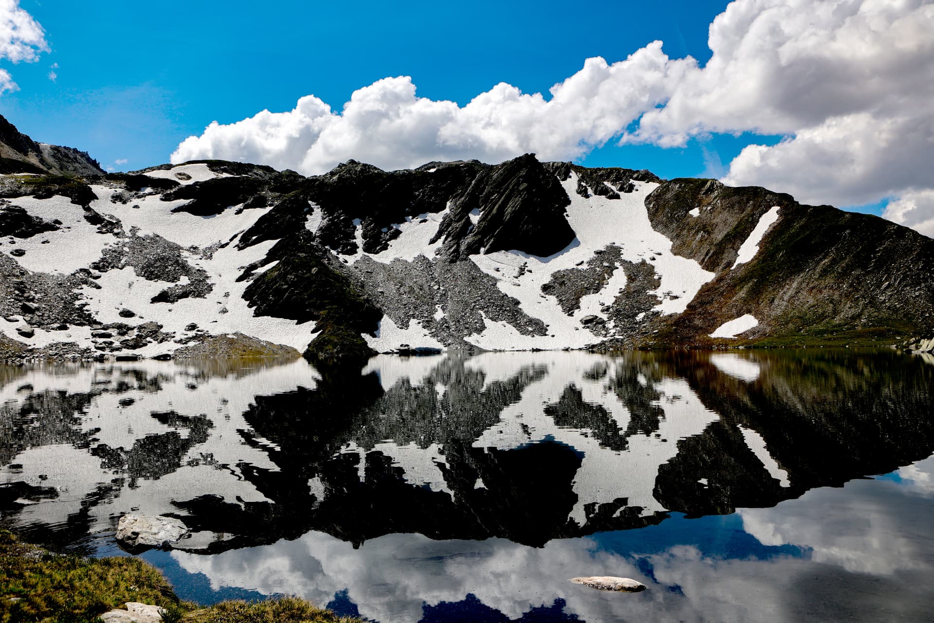 Schneefelder und dunkle Felsen im Spiegel der Lacs de Fenêtre