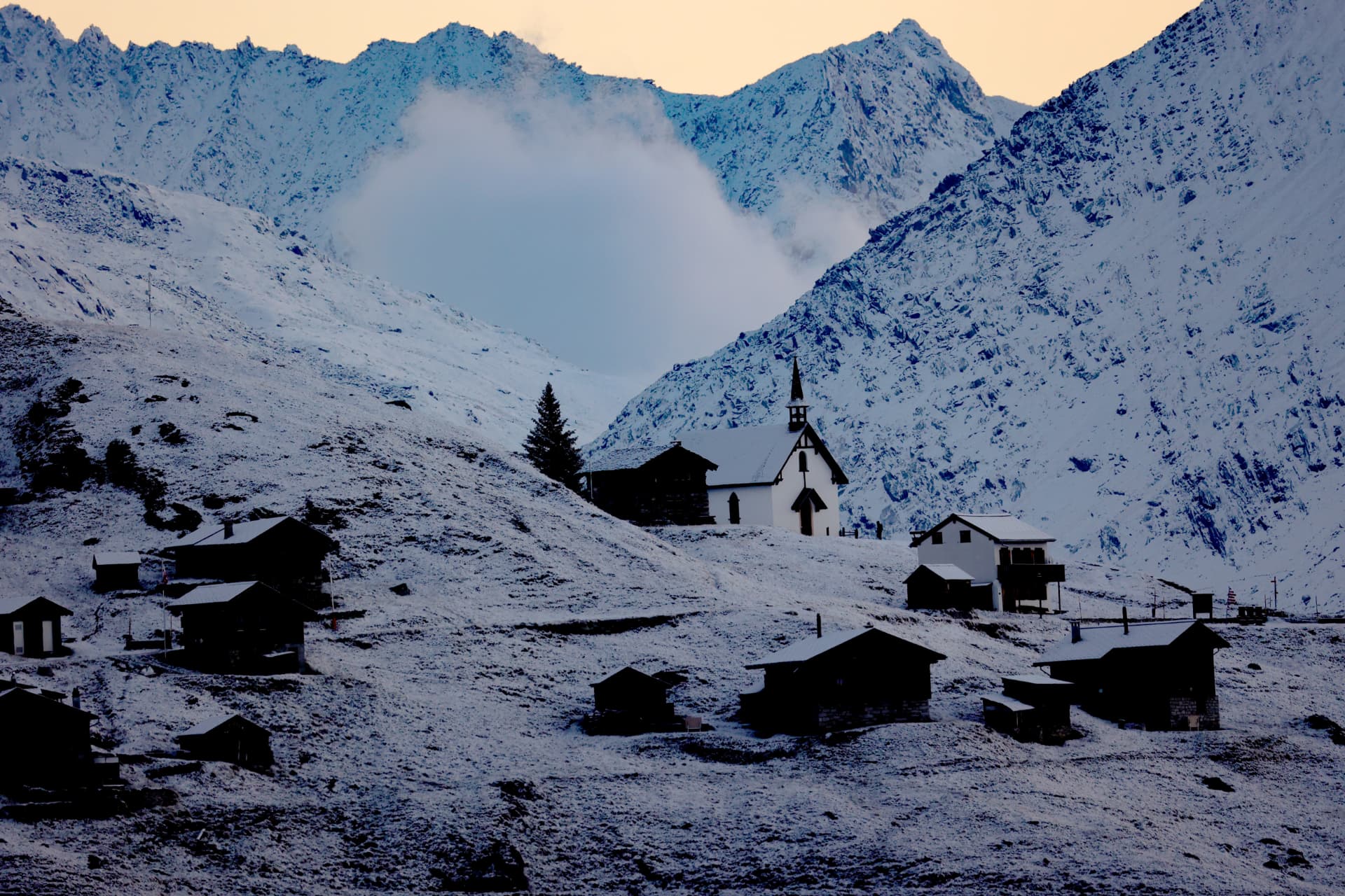 Weiler Belalp mit Kapelle und Holzhütten unter dem ersten Schnee in der Dämmerung