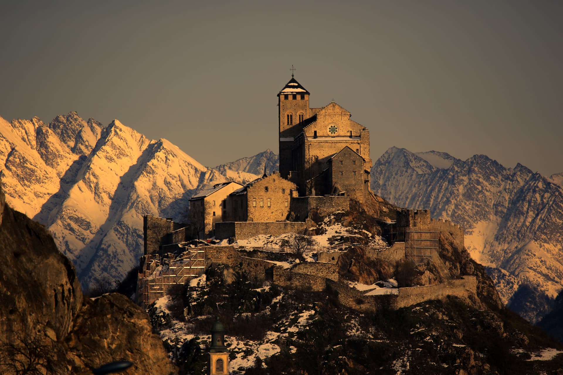 Basilika Valeria im warmen Licht vor den verschneiten Berner Alpen