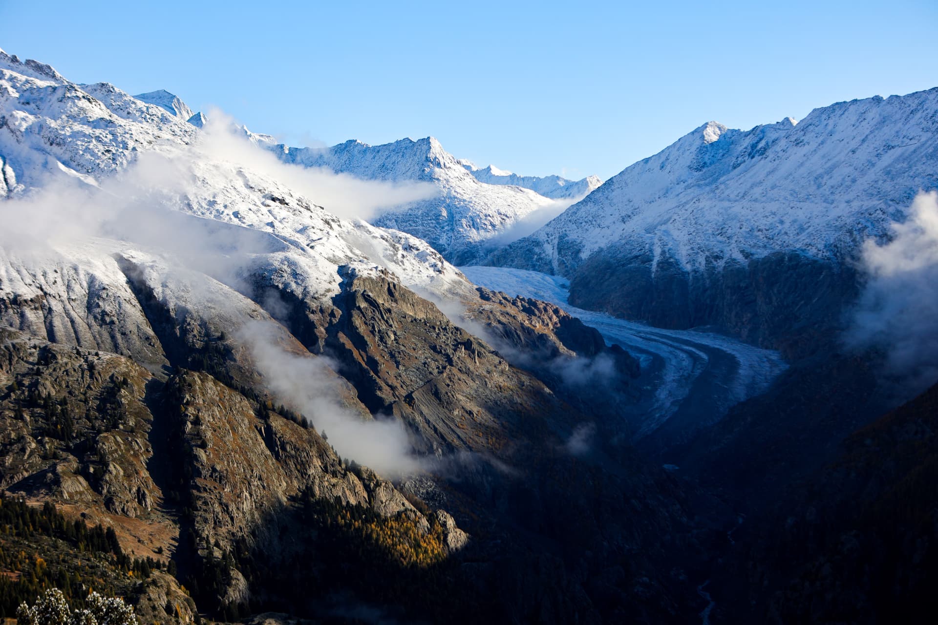 Aletschgletscher im Tal zwischen verschneiten Hängen und Wolken