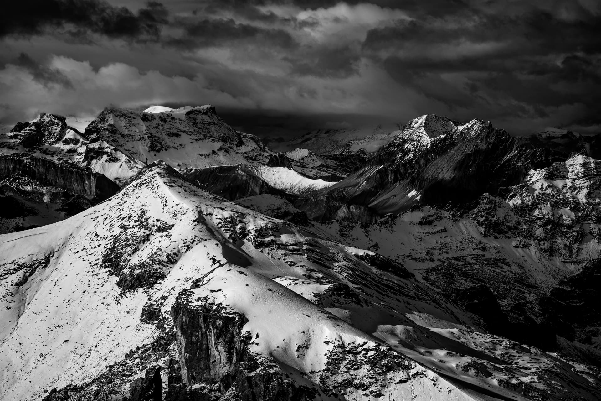Schwarzweiss-Panorama schneebedeckter Grate unter schweren Wolken