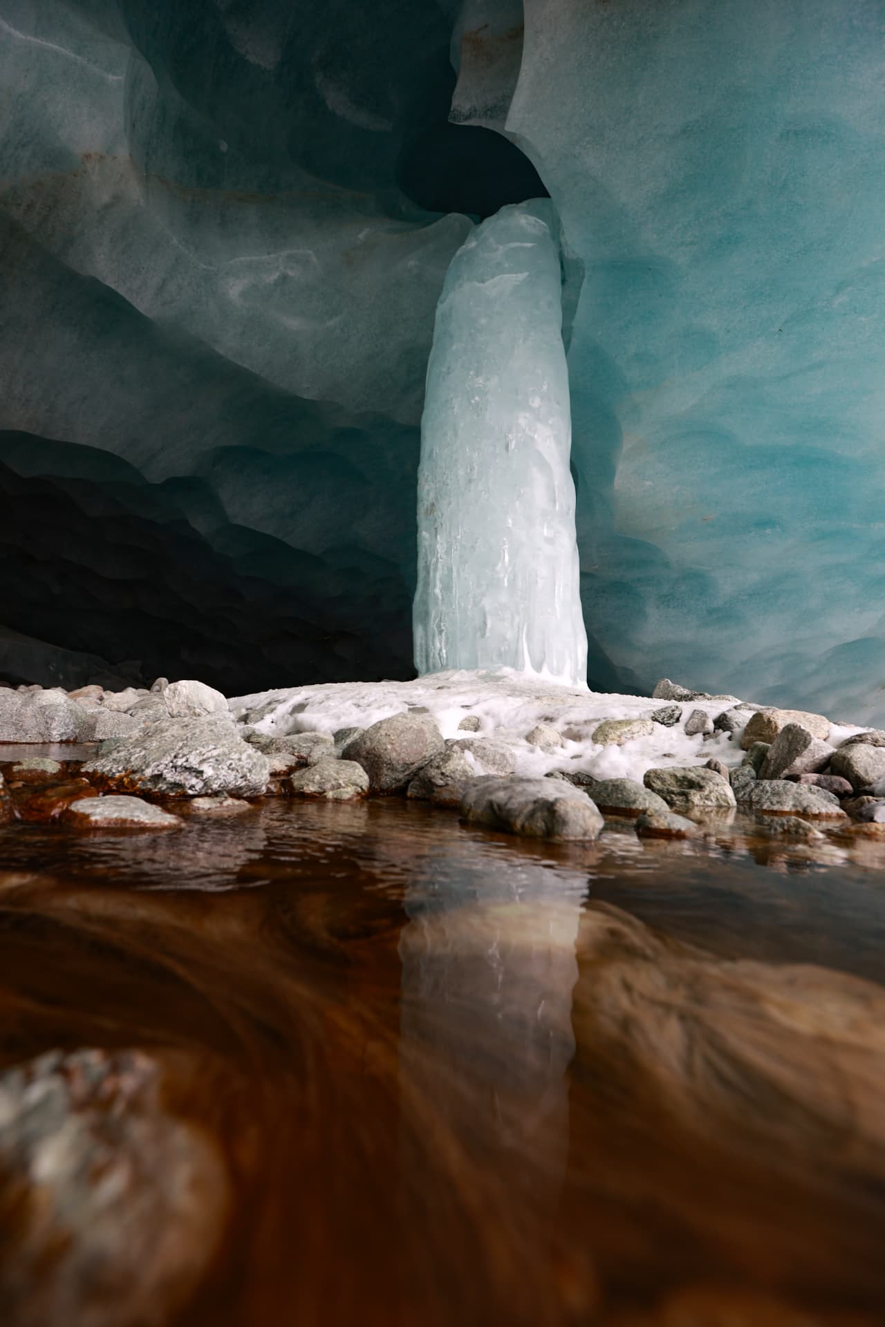 Eissäule in der Höhle und rostfarbenes Wasser am Boden