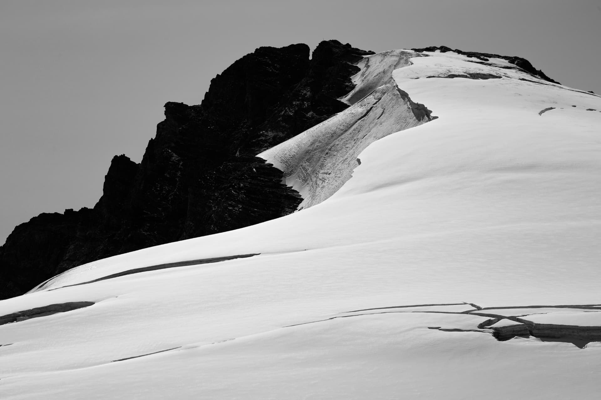 Schwarz-weiße Schneekuppe und Felsbastion über dem Gletscher