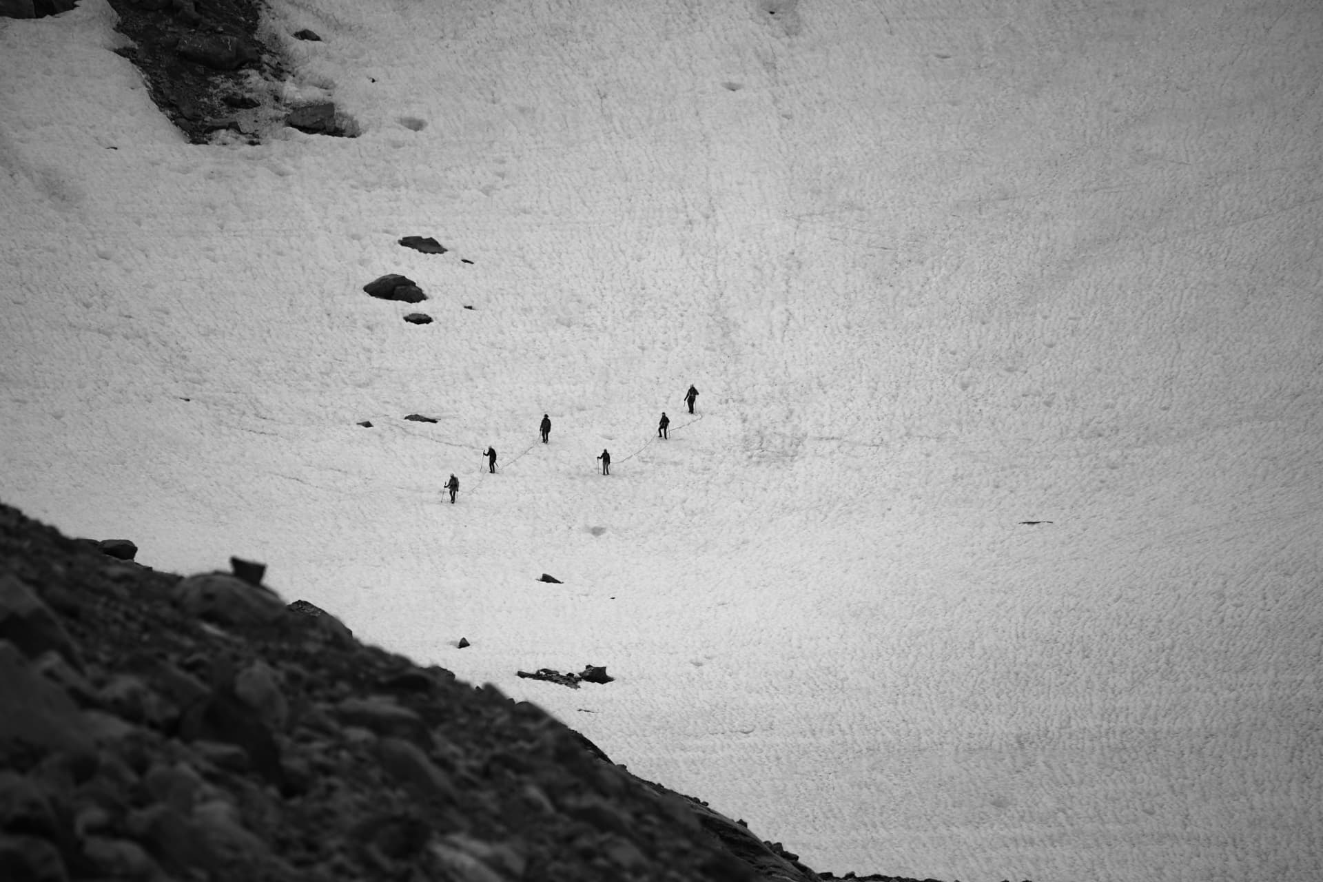Gruppe von Bergsteigern auf einem weiten Schneehang, schwarzweiss