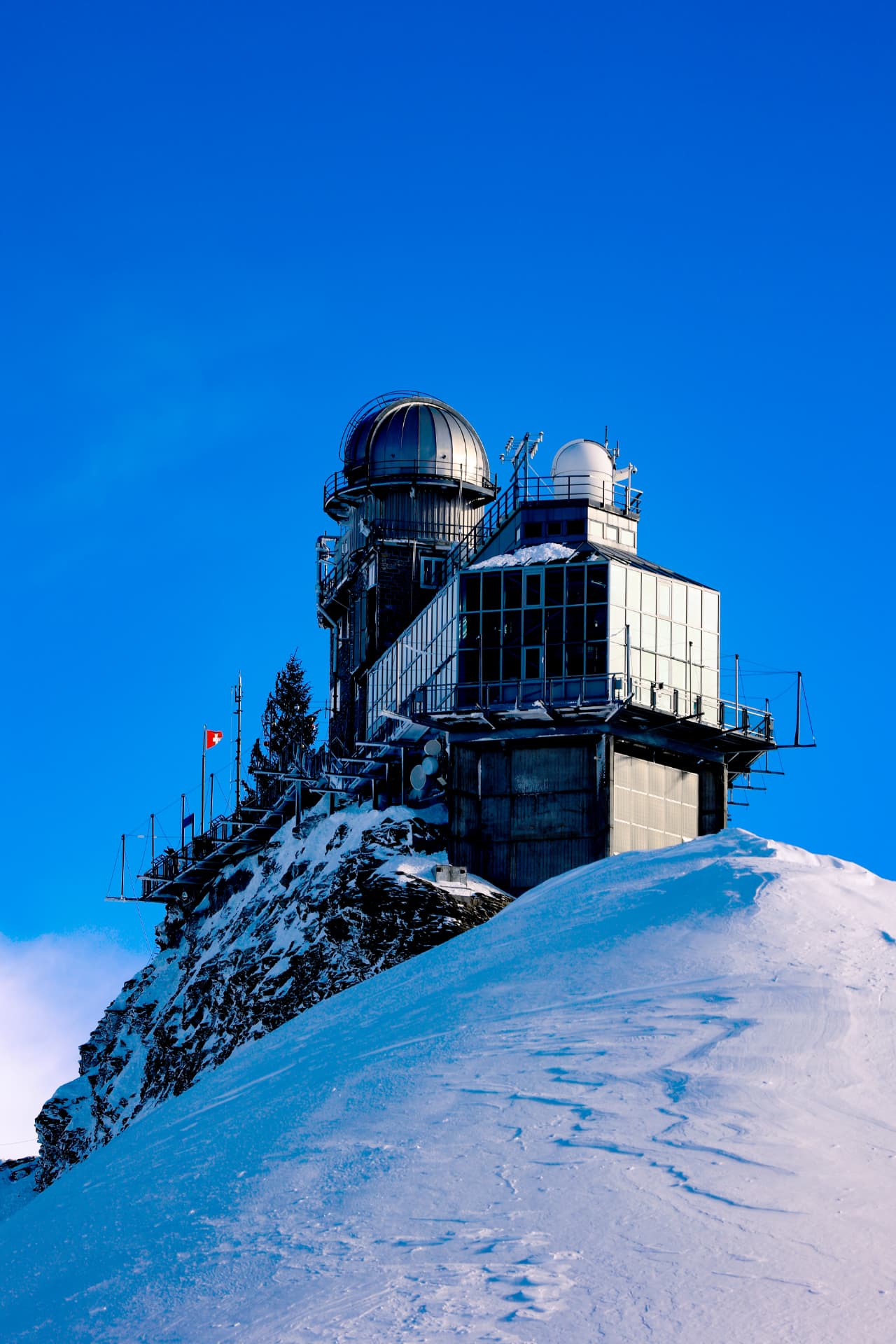 Sphinx-Observatorium über einem Schneehang vor blauem Himmel