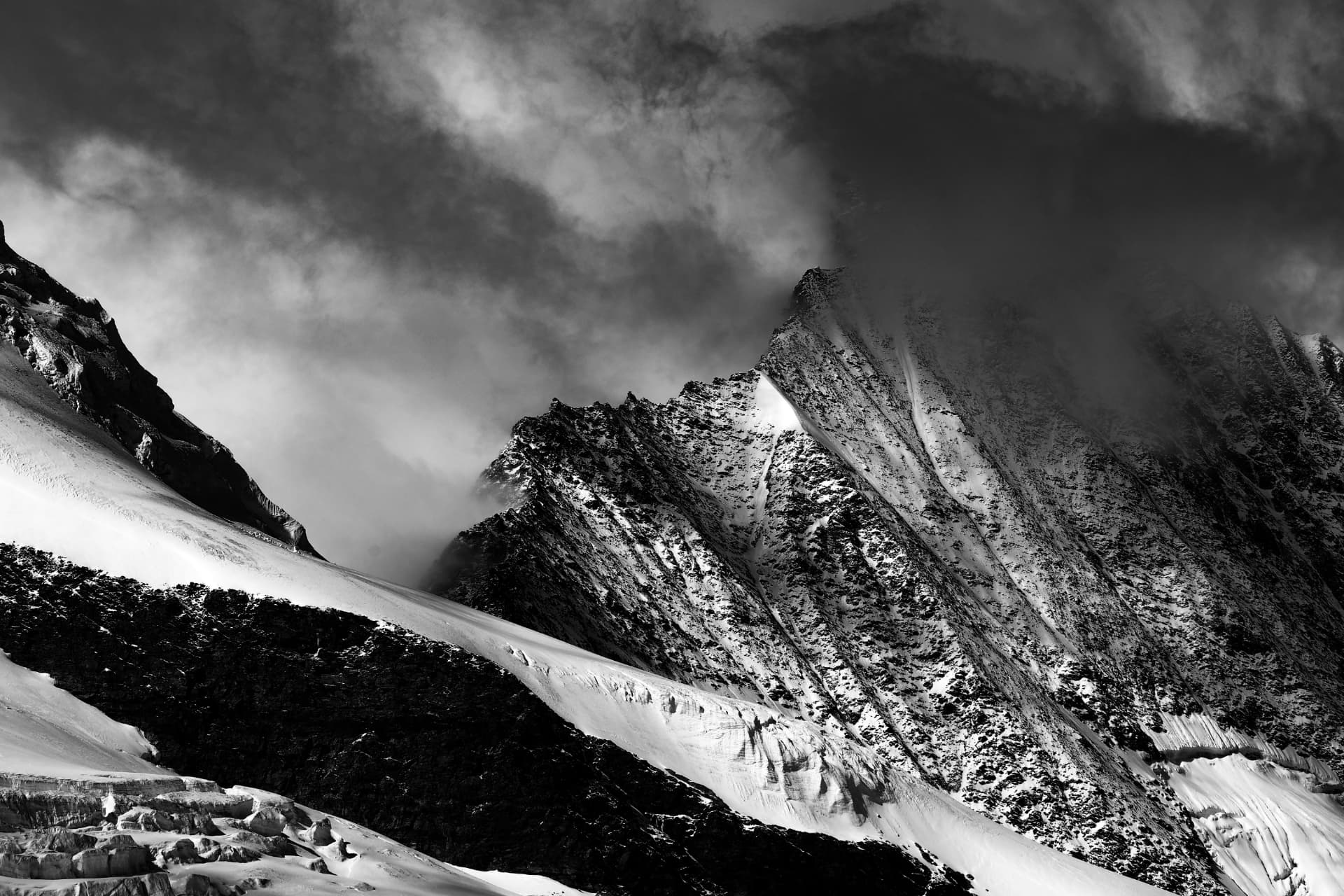 Schwarzweiss-Panorama scharfer, verschneiter Gipfel in Wolken