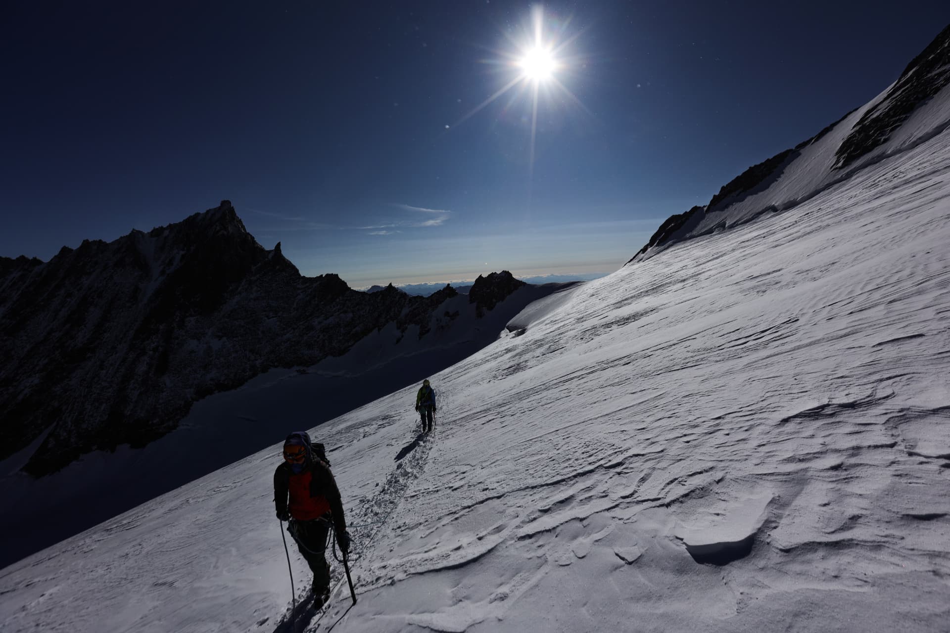 Bergsteiger im Gegenlicht der Morgensonne am Schneehang