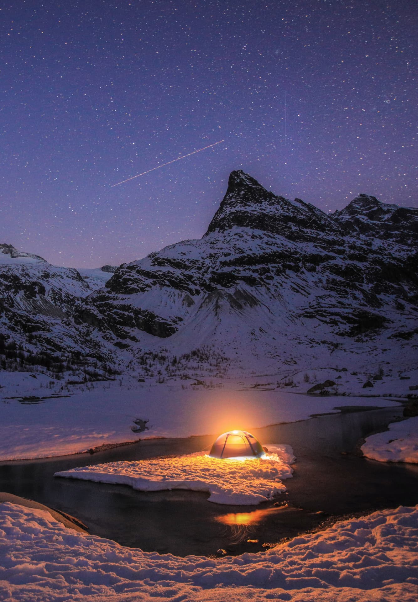 Beleuchtetes Zelt auf einer Schneeinsel am gefrorenen Vorfeld