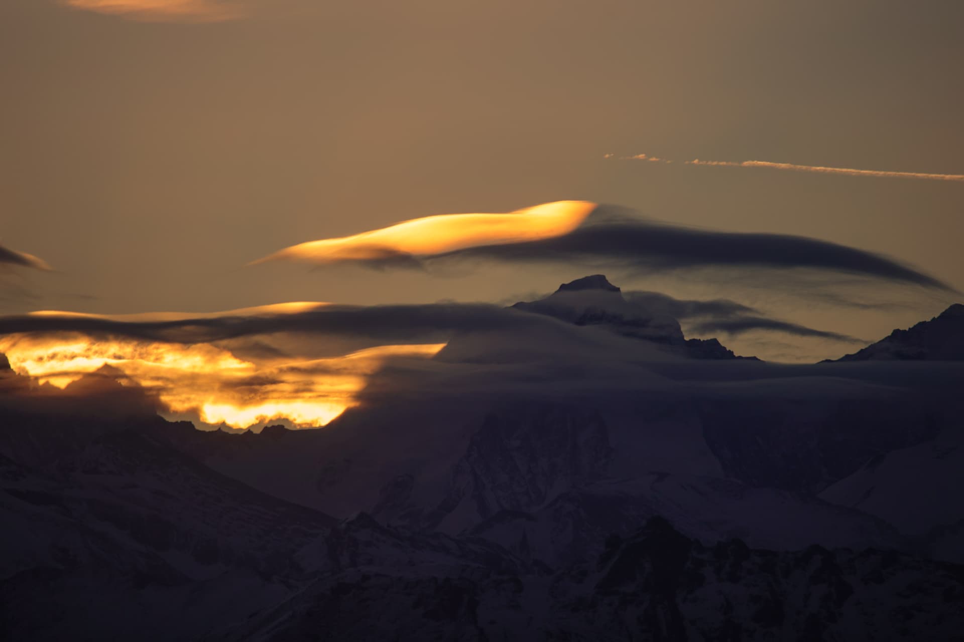 Verschneite Gipfelkuppe in einer Lenticularis-Wolke beim Sonnenaufgang