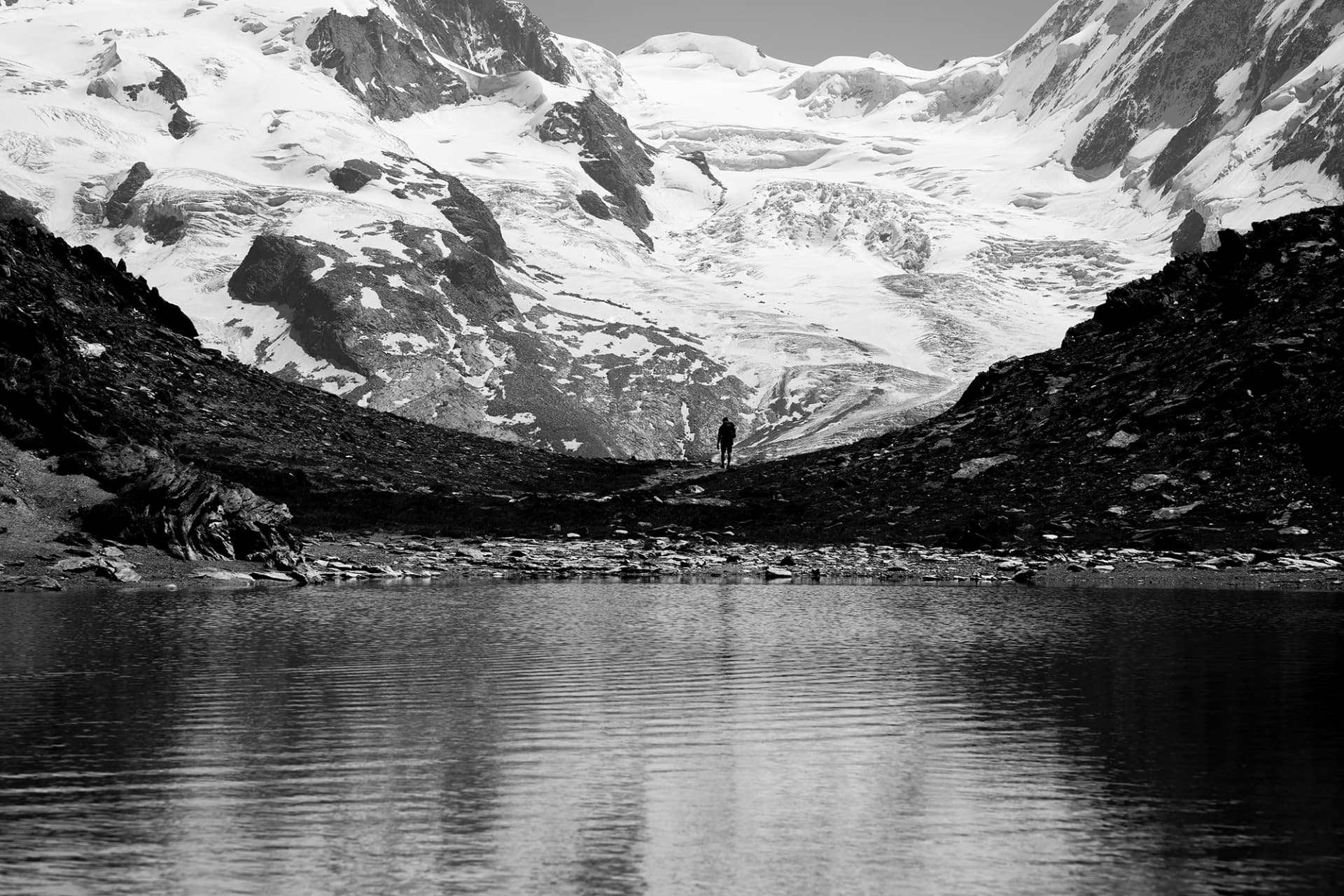 Einsamer Wanderer an einem Bergsee unter dem Monte-Rosa-Gletscher