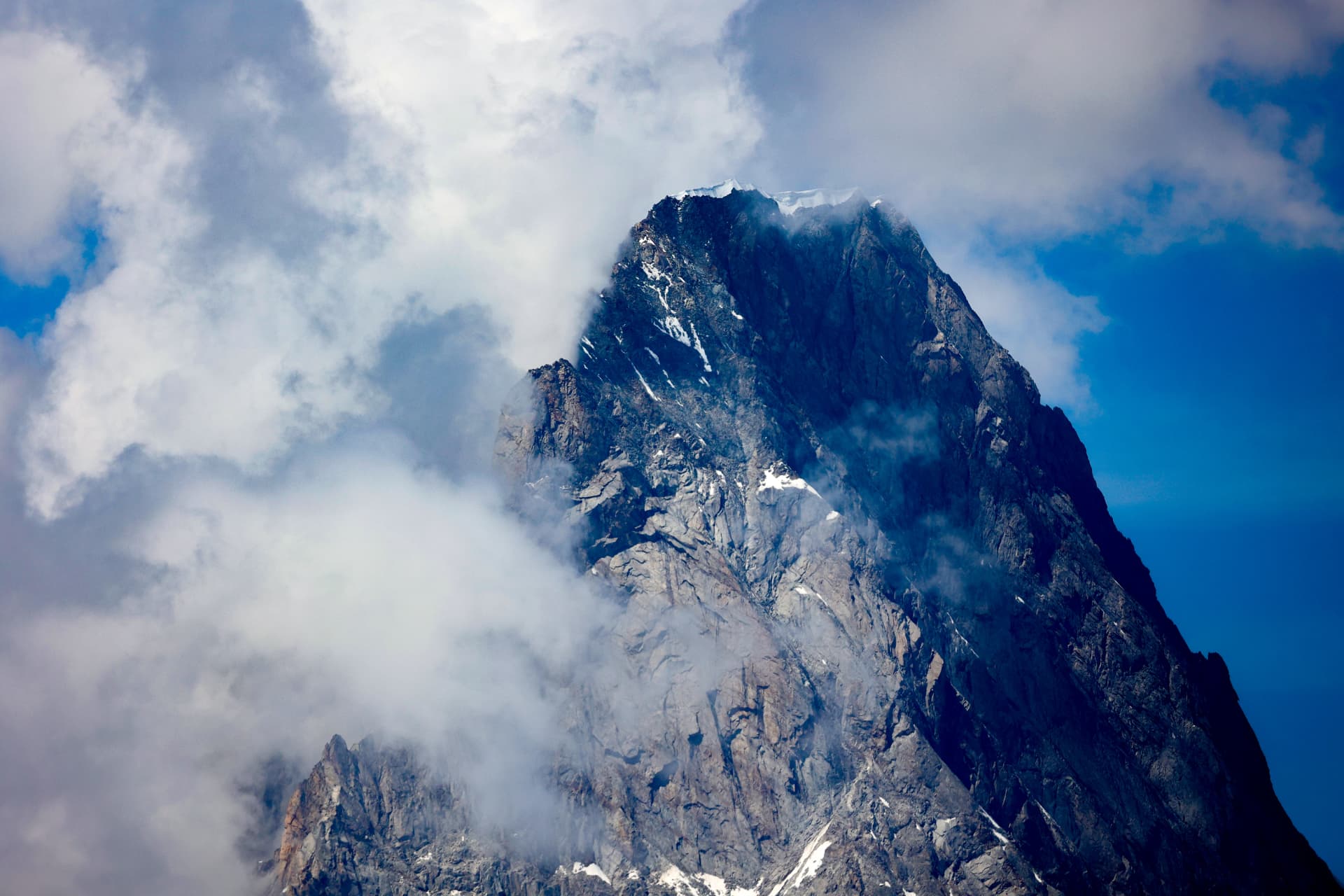 Steiler Felsberg mit Schnee am Gipfel in den Wolken