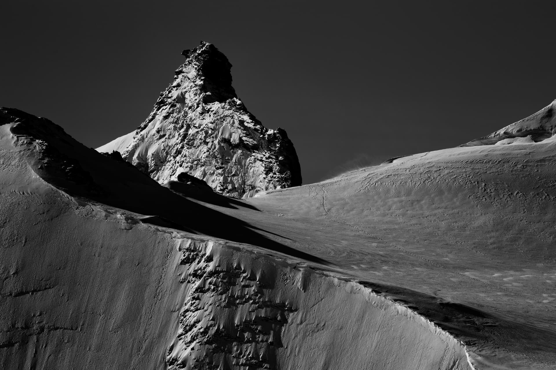 Das Matterhorn in Schwarz-Weiß über verschneiten Hängen mit Skispuren